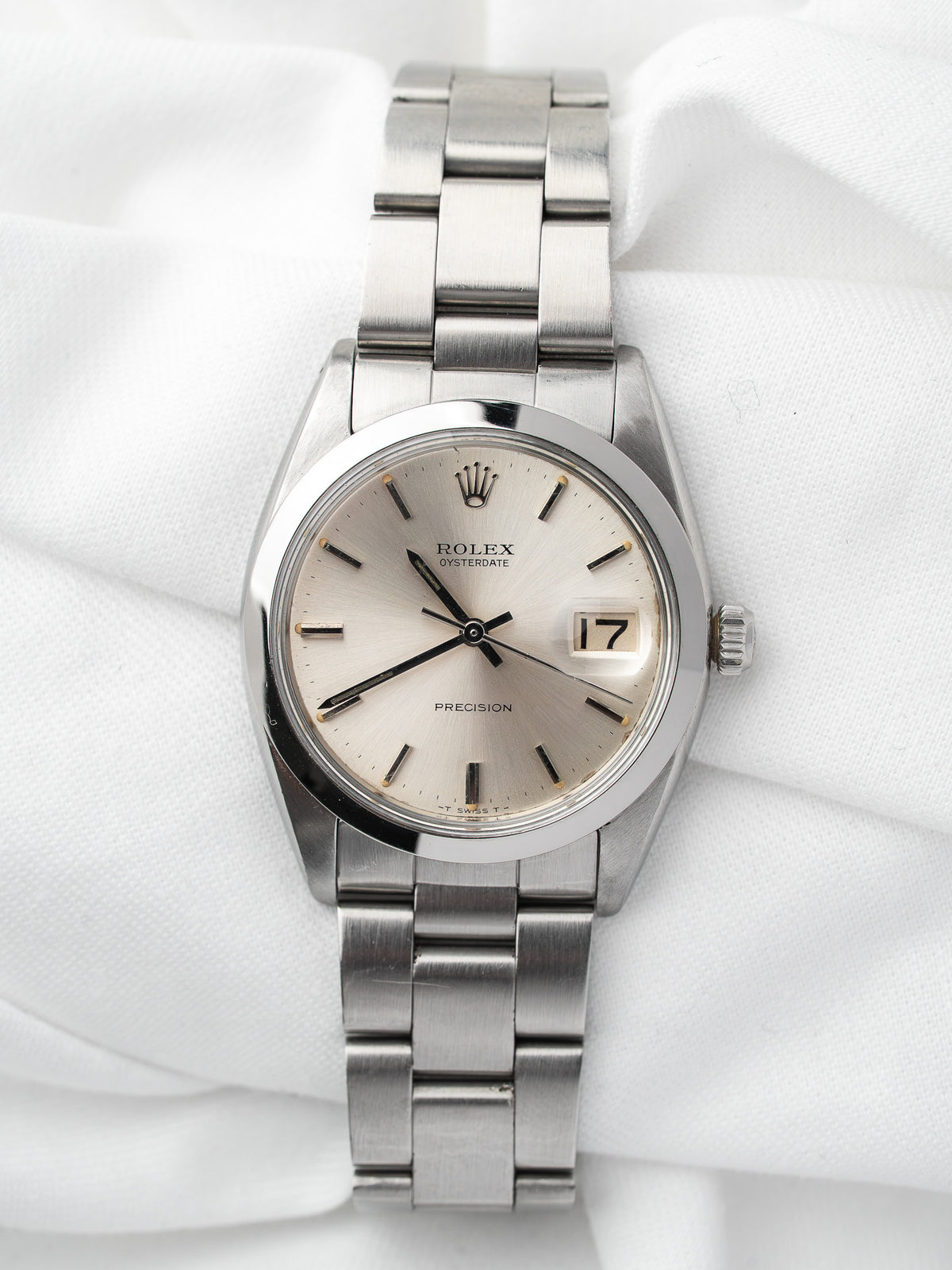 Montre Rolex Oysterdate vintage en acier, cadran champagne, posée sur tissu blanc