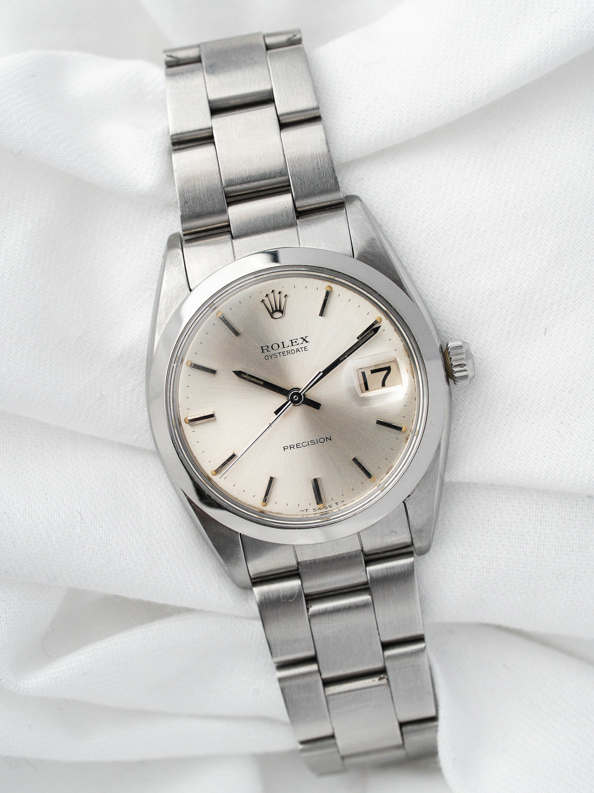 Montre Rolex Oysterdate vintage en acier, cadran argenté, posée sur un tissu blanc
