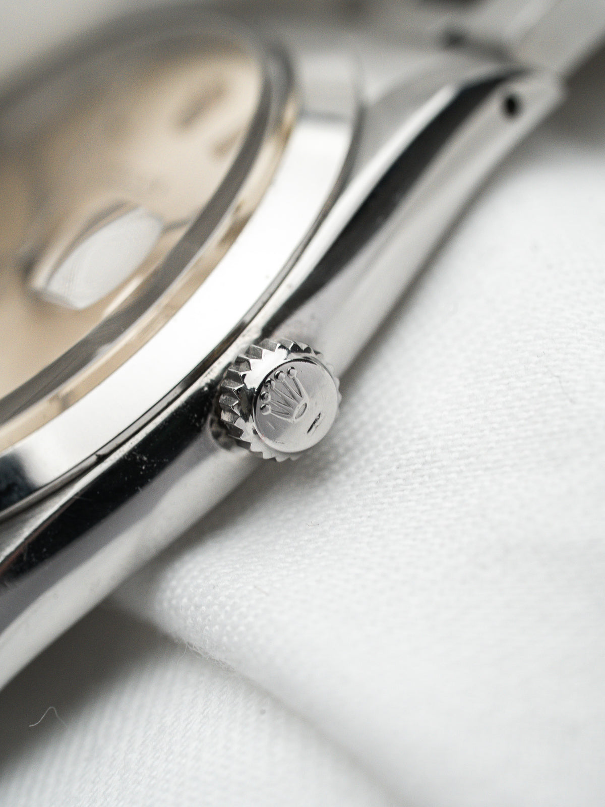 Détail de la couronne en acier d'une montre Rolex vintage sur fond blanc