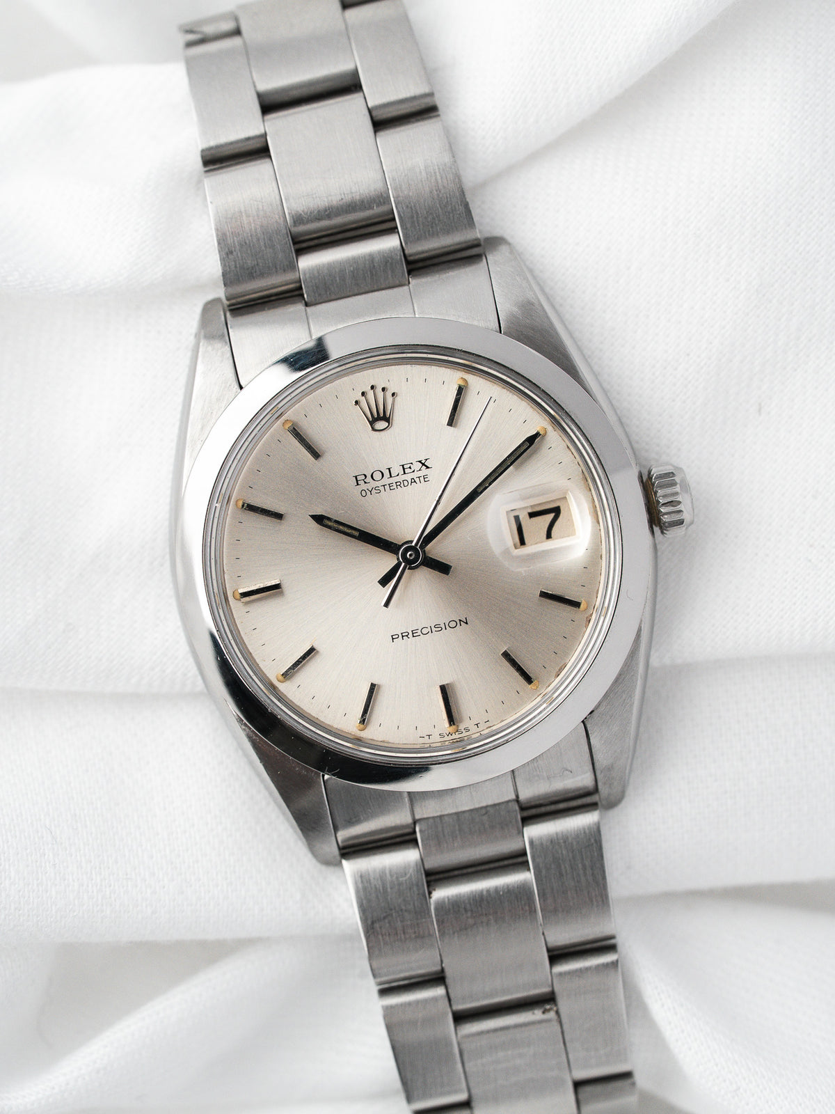 Montre Rolex Oysterdate vintage en acier, cadran argenté, posée sur tissu blanc