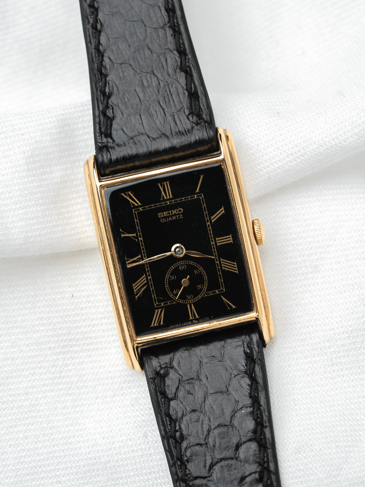 Seiko Quartz vintage watch with gold case, black dial, and textured leather strap