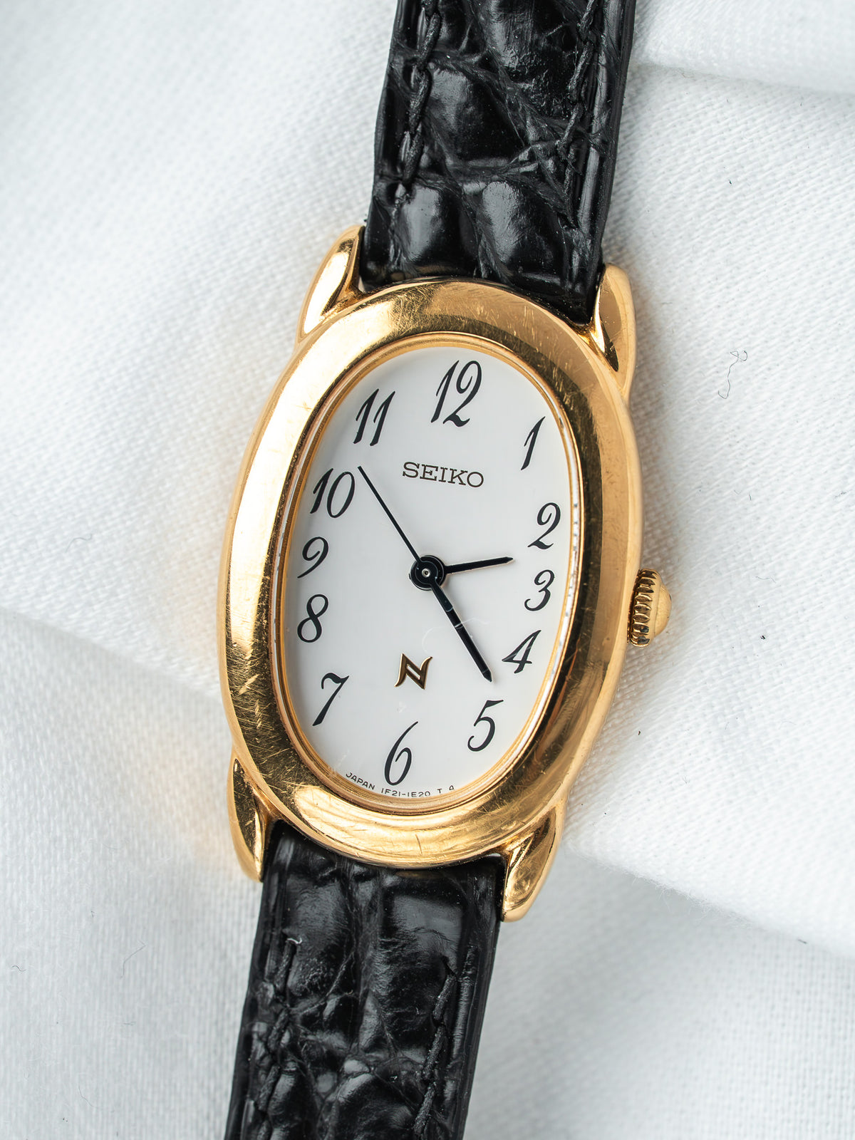 Montre Seiko vintage, boîtier ovale plaqué or, cadran blanc et bracelet cuir noir
