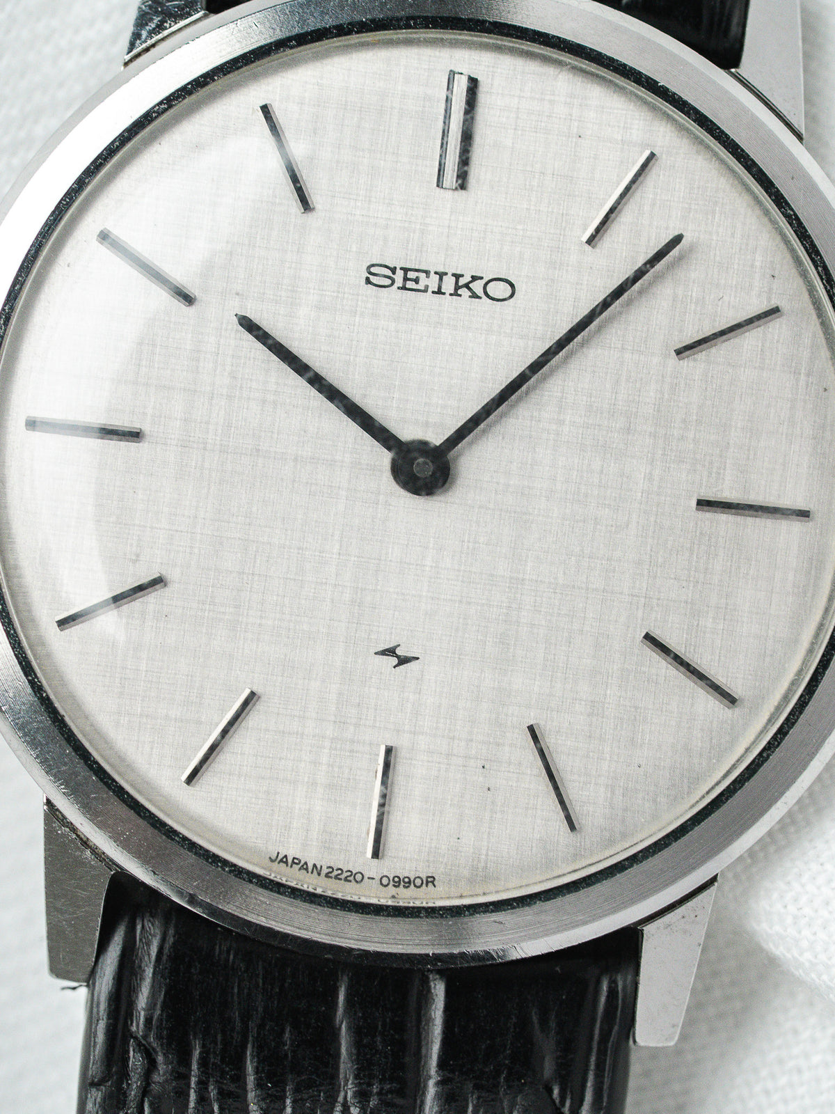 Seiko vintage watch with silver textured dial, black hands, and black leather strap