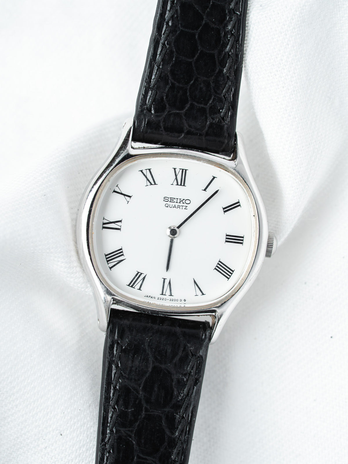Seiko Quartz vintage watch with white dial, Roman numerals, black textured strap