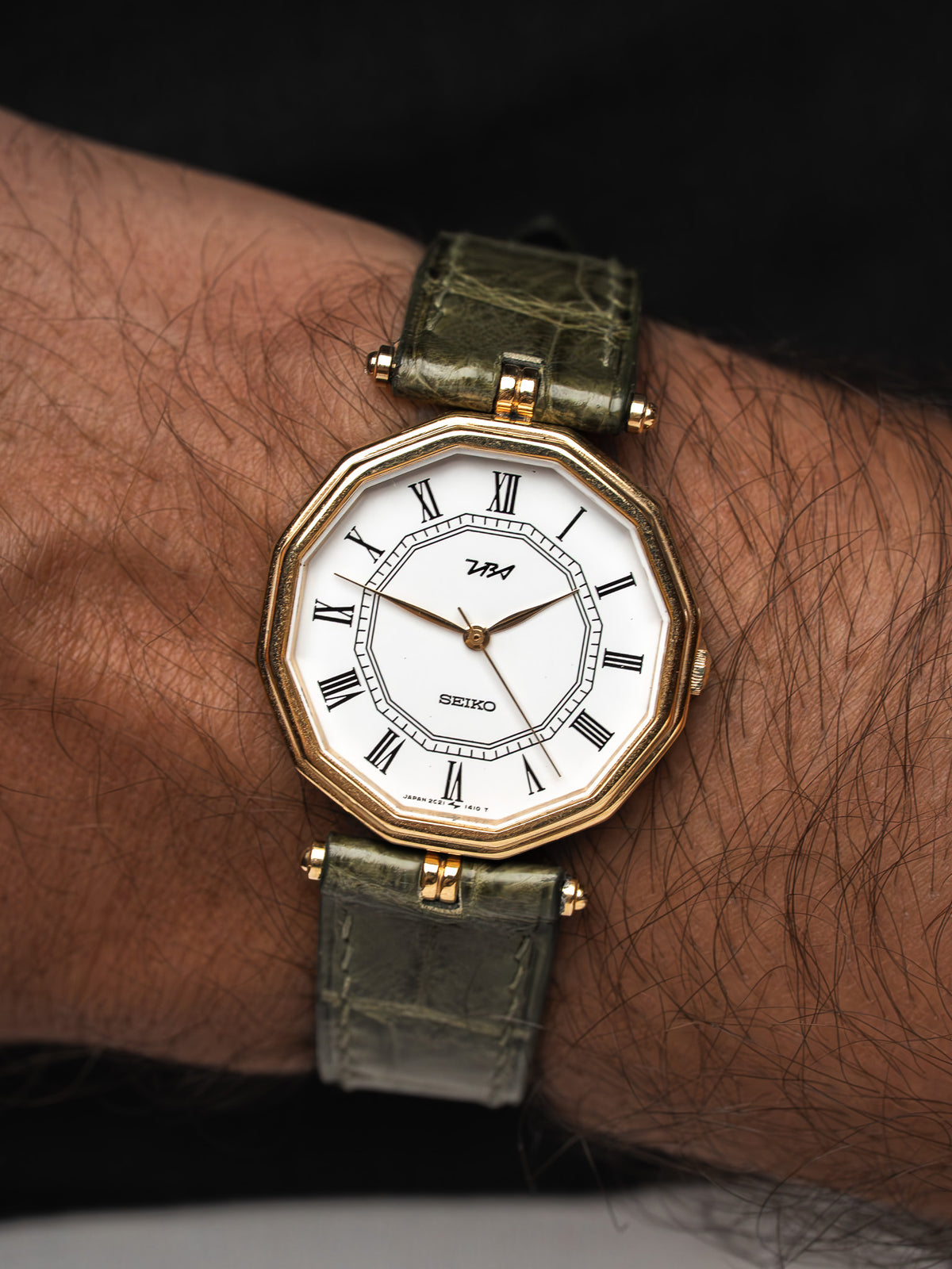 Montre Seiko vintage au boîtier octogonal doré avec bracelet en cuir vert olive.