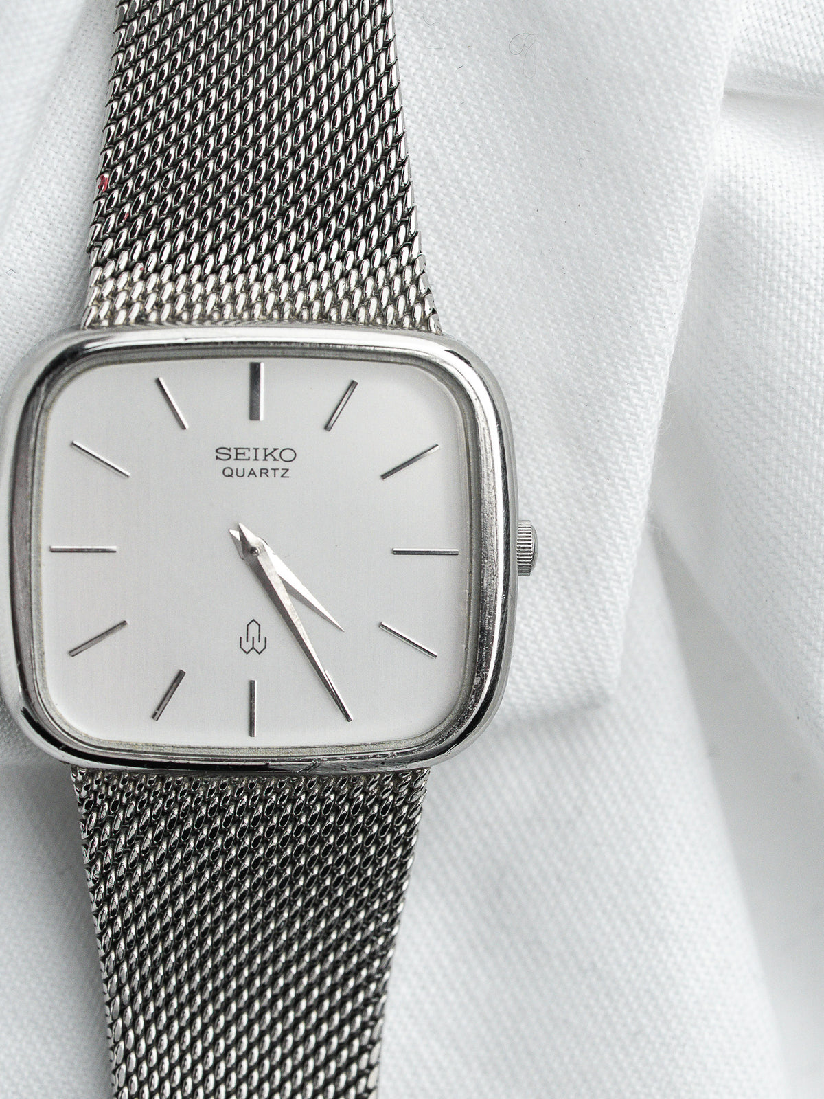 Montre Seiko Quartz vintage, boîtier rectangulaire en acier, cadran blanc et bracelet milanais