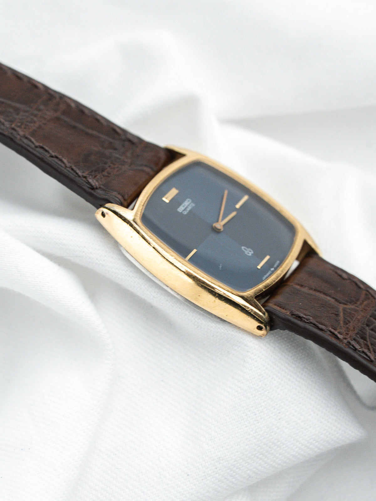 Montre vintage au boîtier doré, cadran bleu et bracelet en cuir marron texturé.