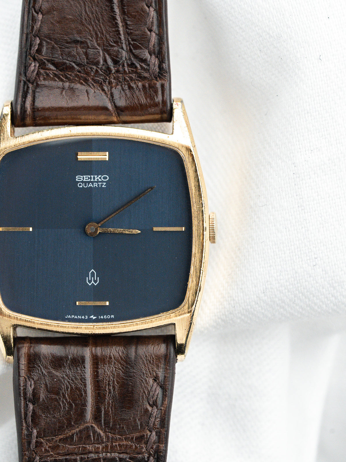 Montre Seiko Quartz vintage avec cadran bleu, boîtier doré et bracelet en cuir brun.