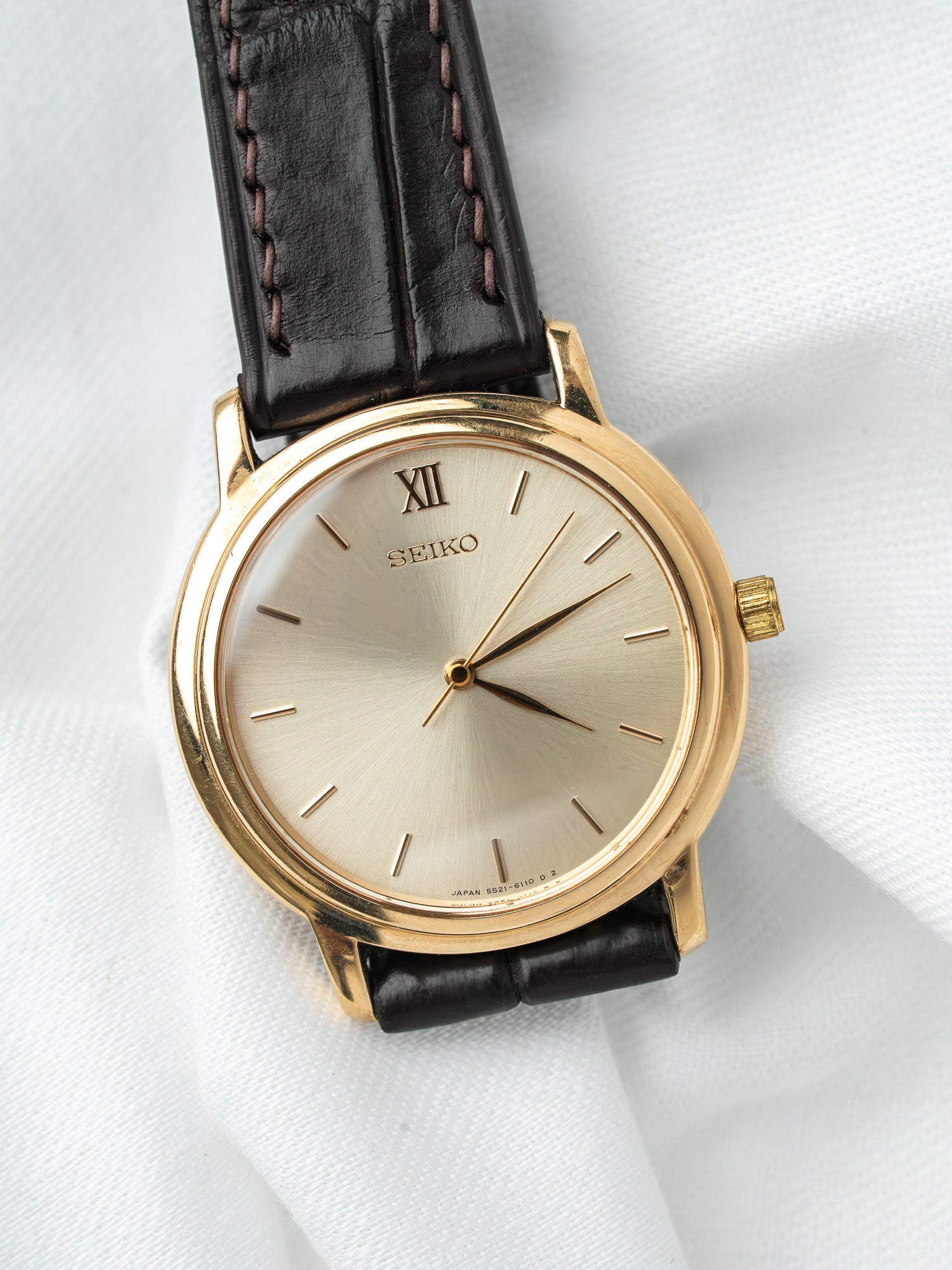 Seiko vintage watch with gold case, silver dial, Roman XII, black leather strap