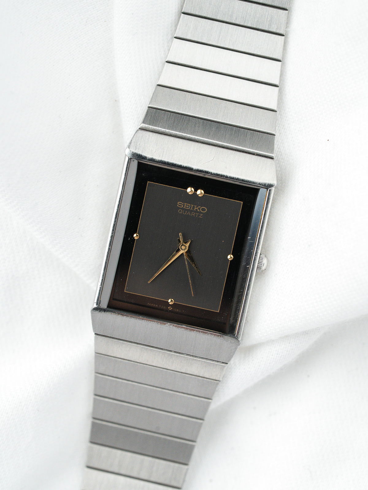 Montre Seiko Quartz vintage avec cadran noir rectangulaire et bracelet en acier argenté.