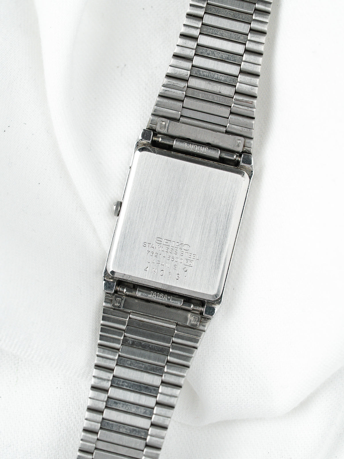 Dos d'une montre vintage en acier inoxydable avec bracelet à maillons argentés.