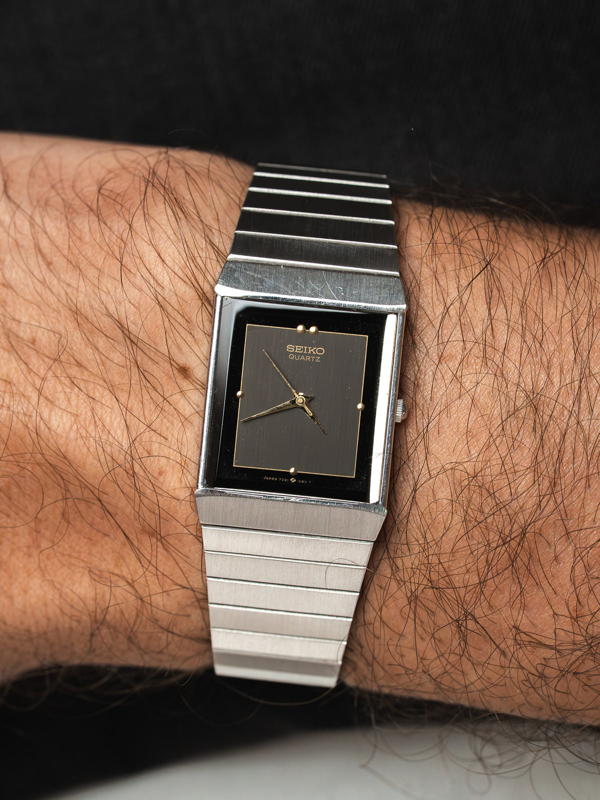 Montre Seiko Quartz vintage avec cadran rectangulaire noir et bracelet en acier argenté.