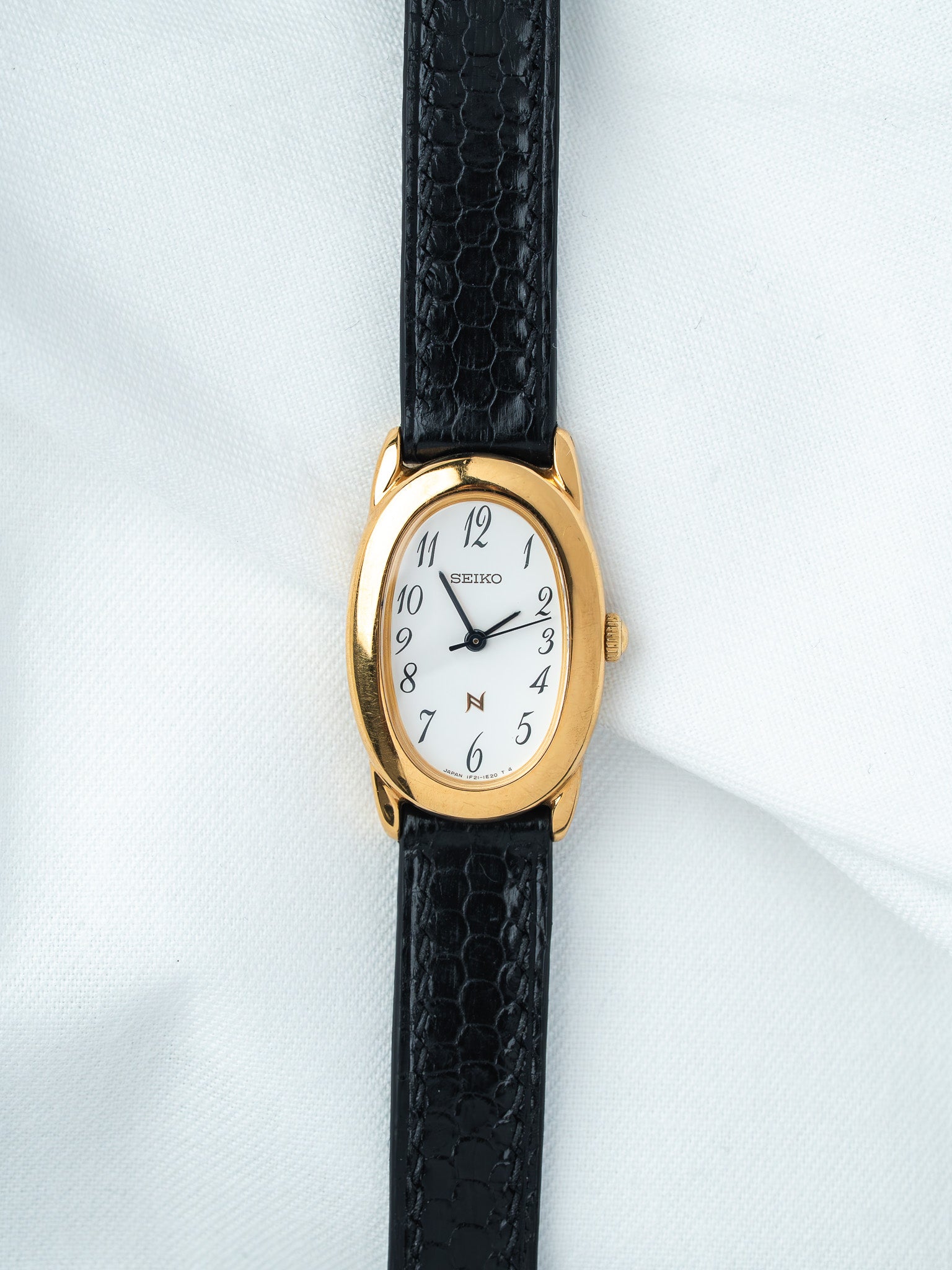 Seiko vintage watch with gold case, white dial, black snake leather strap