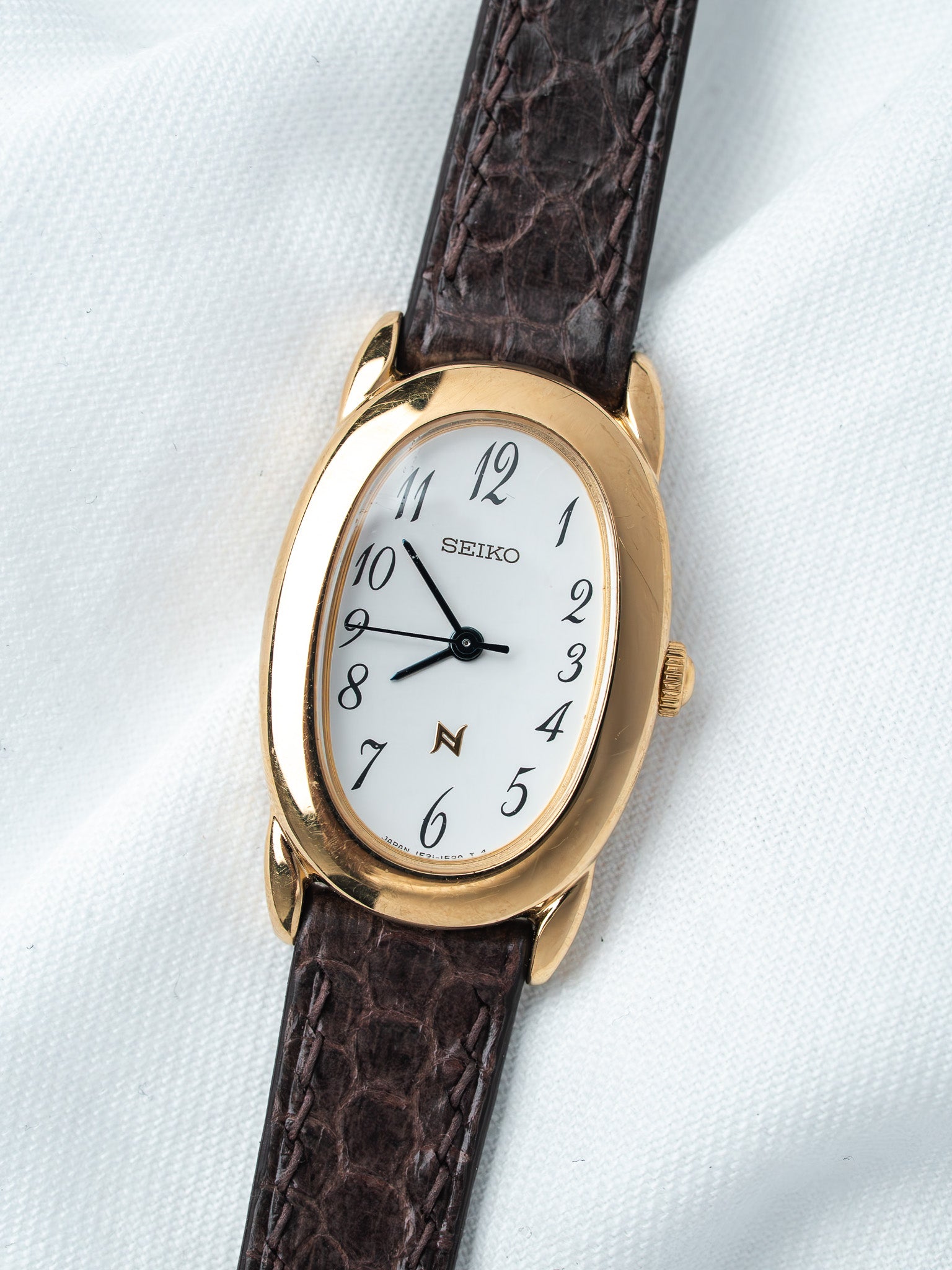 Seiko vintage watch with gold case, white dial, and brown leather strap