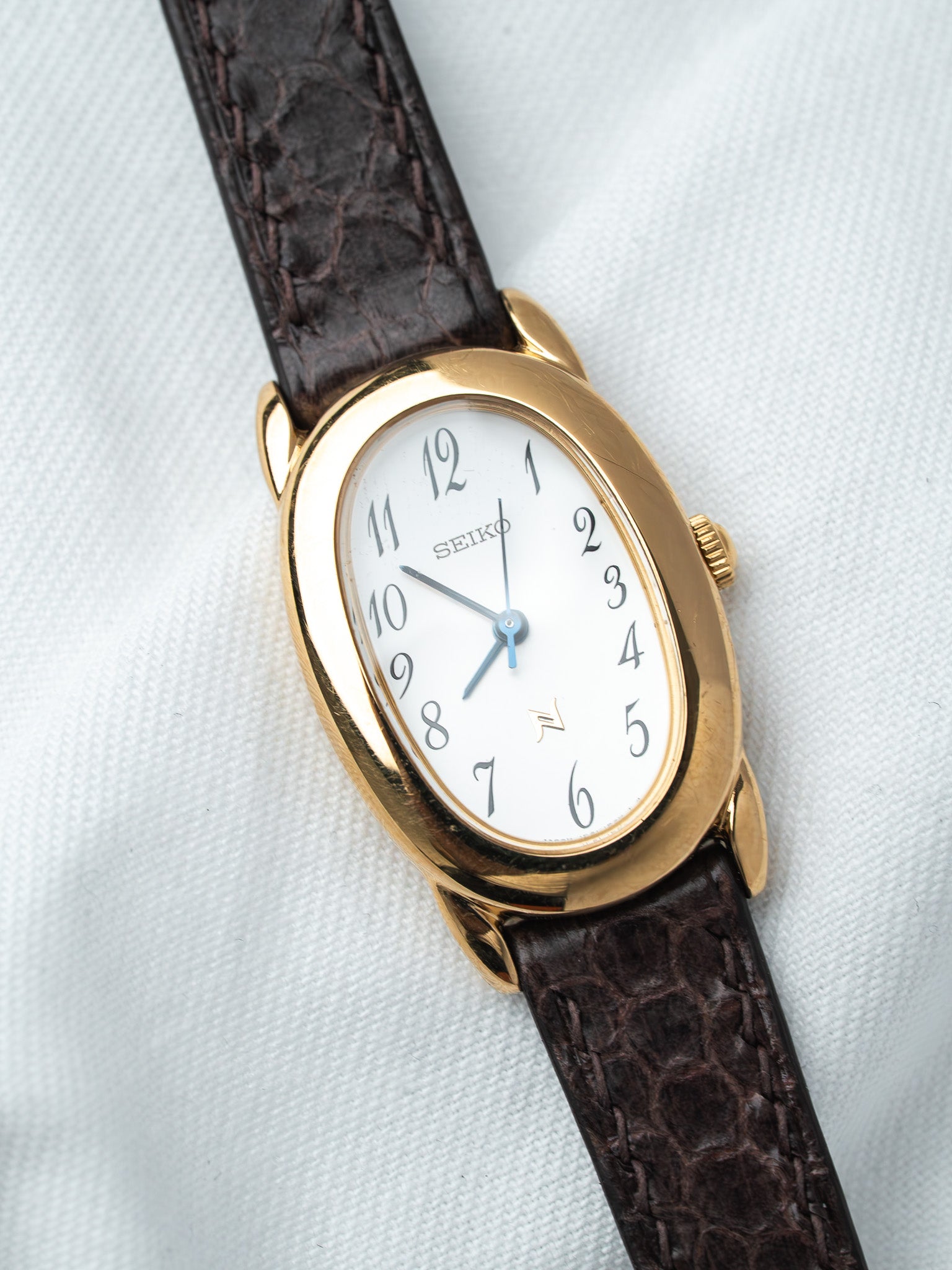 Seiko vintage watch with gold case, white dial, and brown leather strap