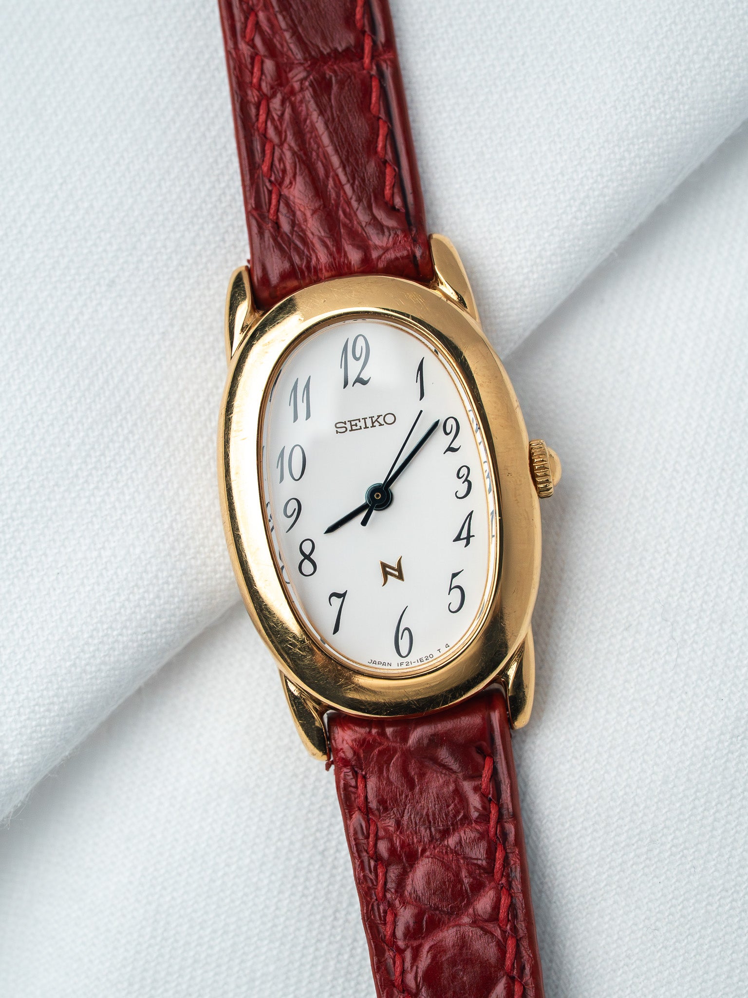 Seiko vintage watch with gold case, white dial, and red leather strap