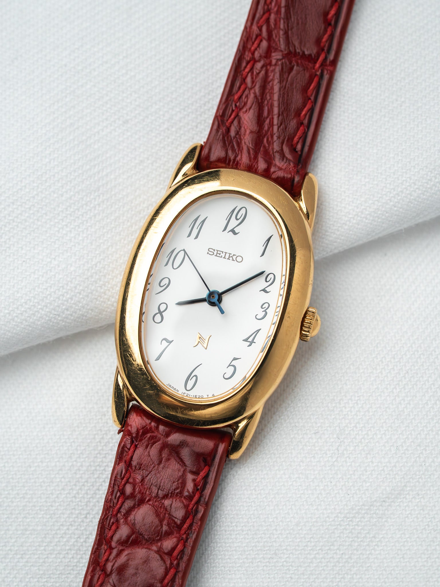 Seiko vintage watch with gold case, white dial, and red leather strap