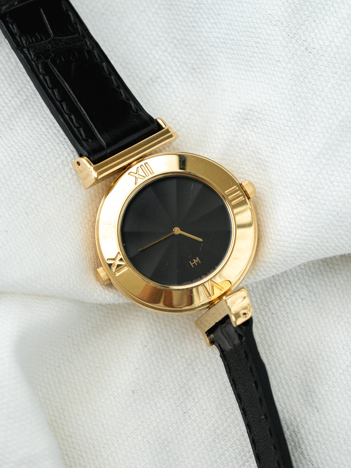 Vintage HM watch with gold case, black sunburst dial, Roman numerals, black leather strap