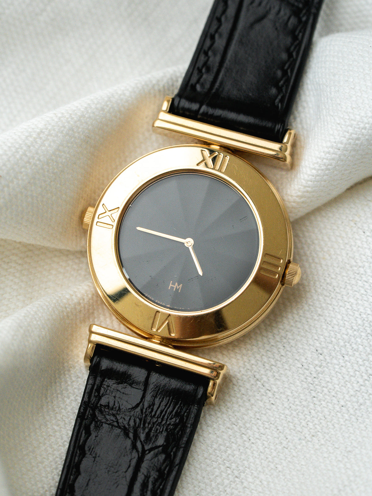 Montre HM vintage en or jaune, cadran gris, bracelet cuir noir texturé
