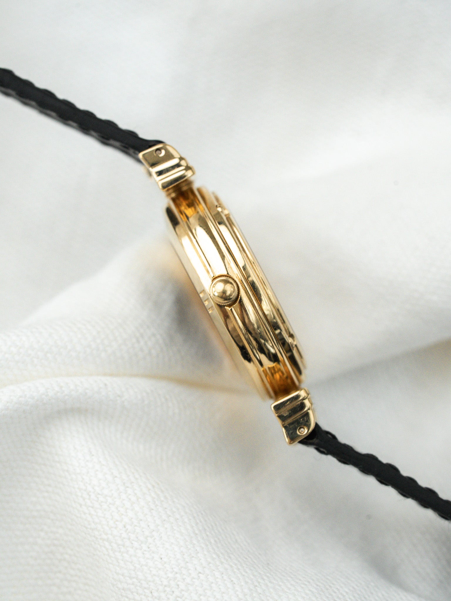 Cartier Tank vintage gold case with black leather strap on white fabric