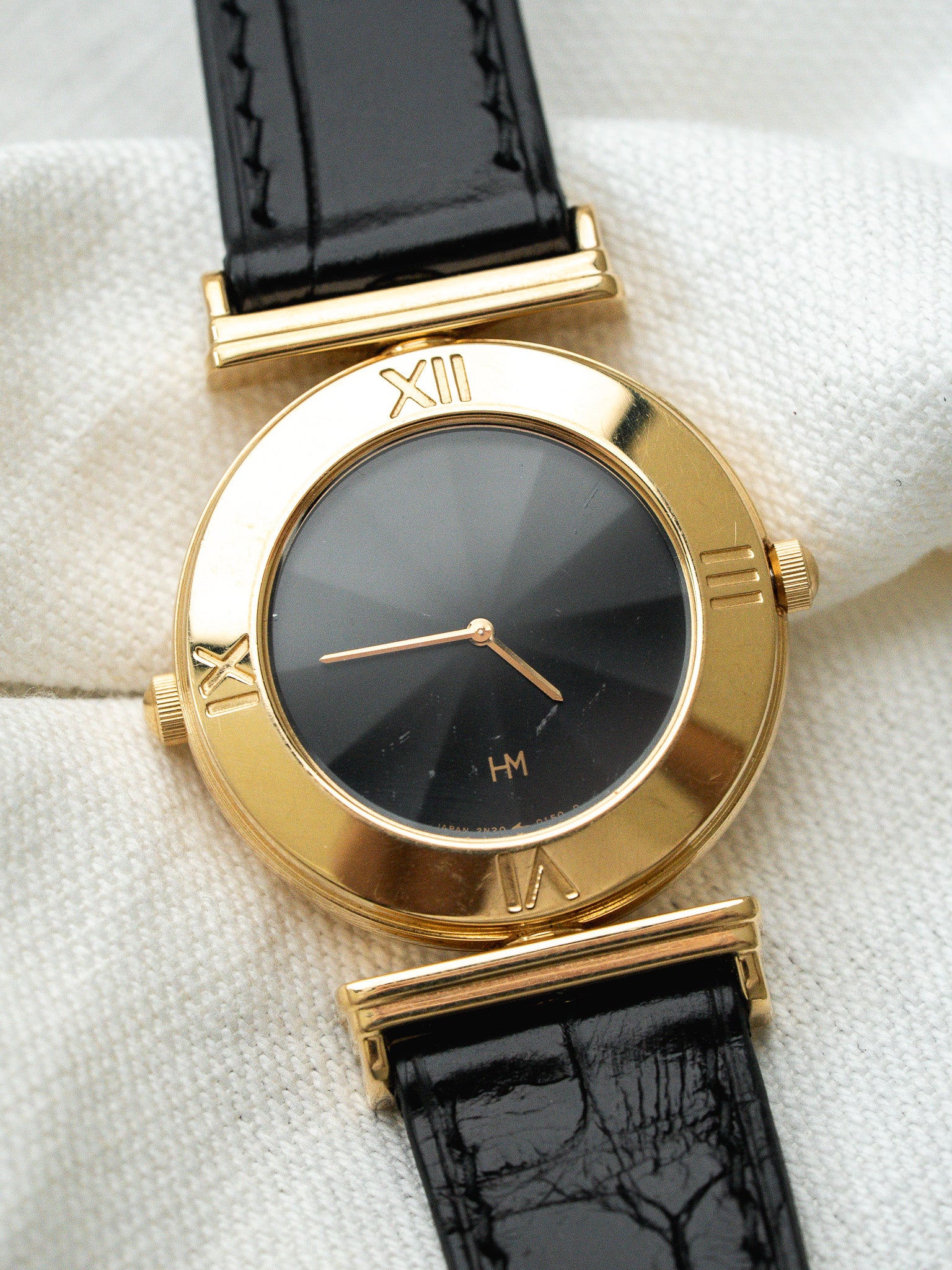 Montre HM vintage en or jaune, cadran noir, bracelet cuir noir texturé