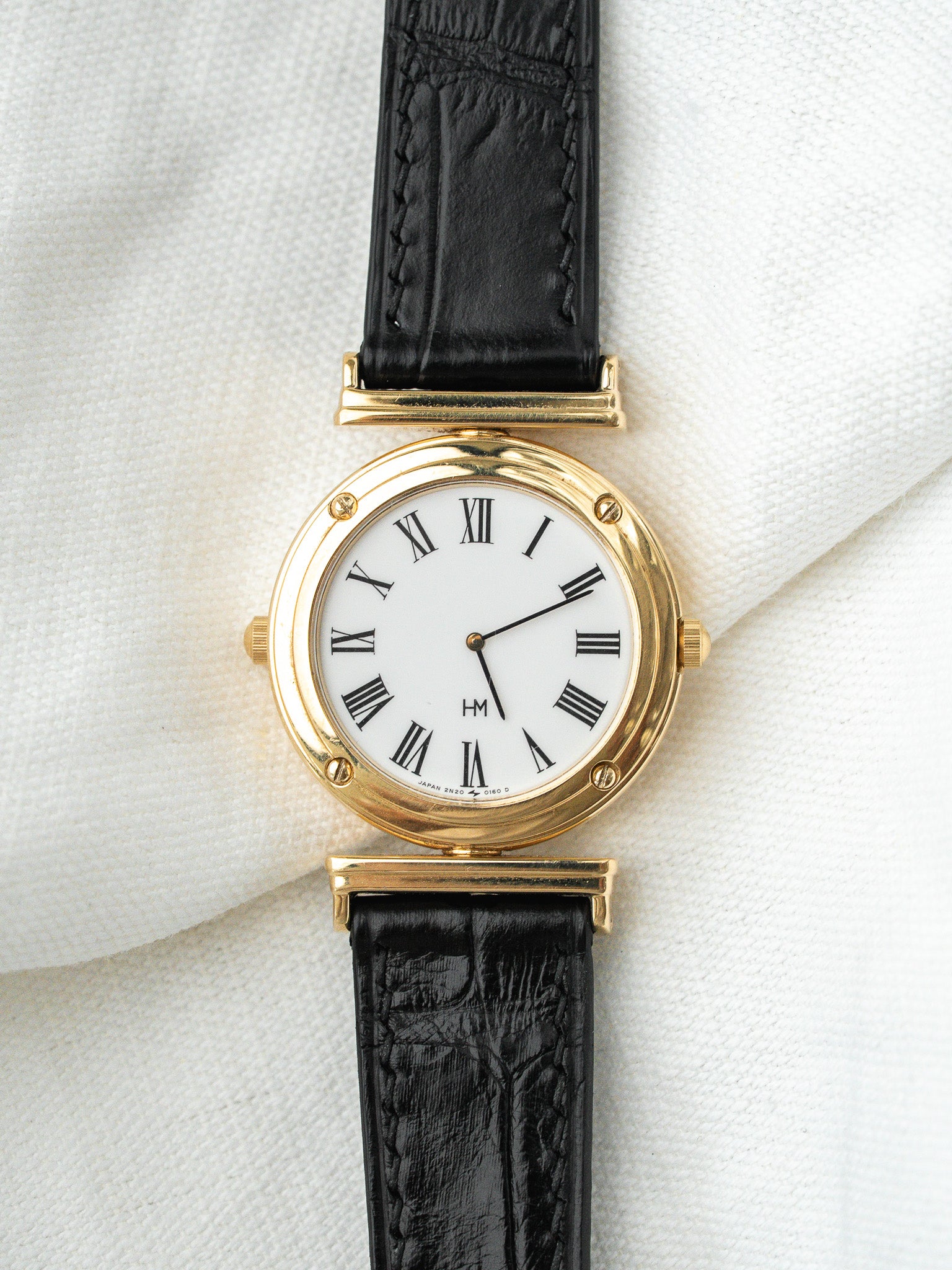 Montre HM vintage en or jaune, cadran blanc chiffres romains, bracelet cuir noir