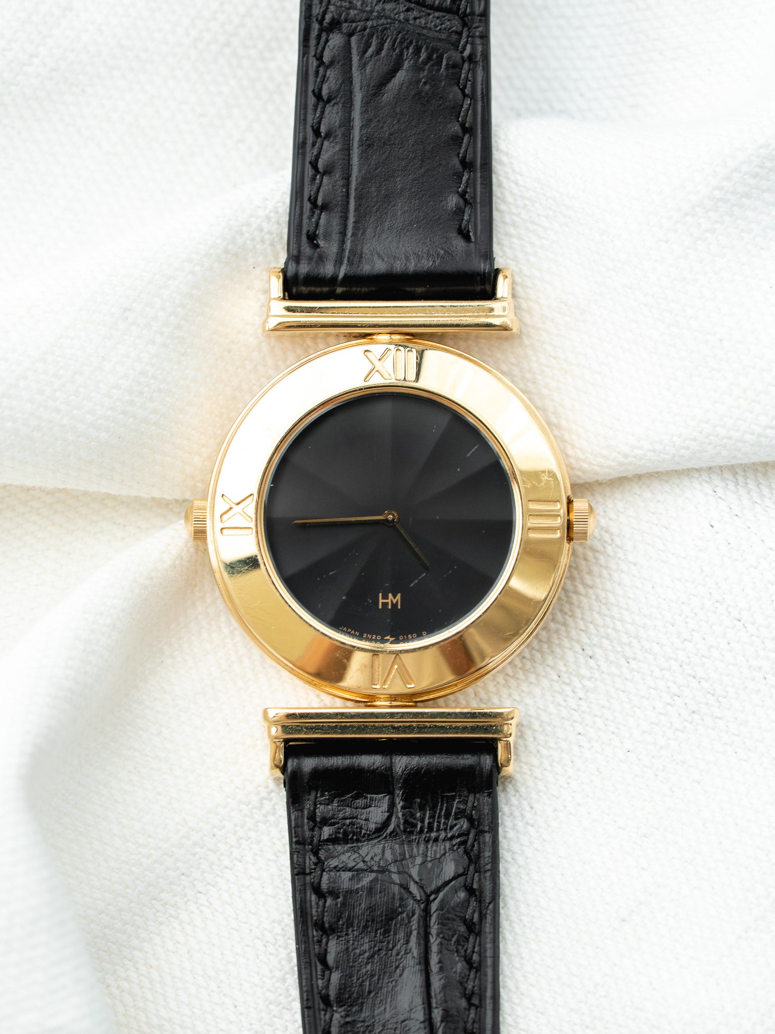 Montre HM vintage en or jaune, cadran noir soleillé, bracelet cuir noir