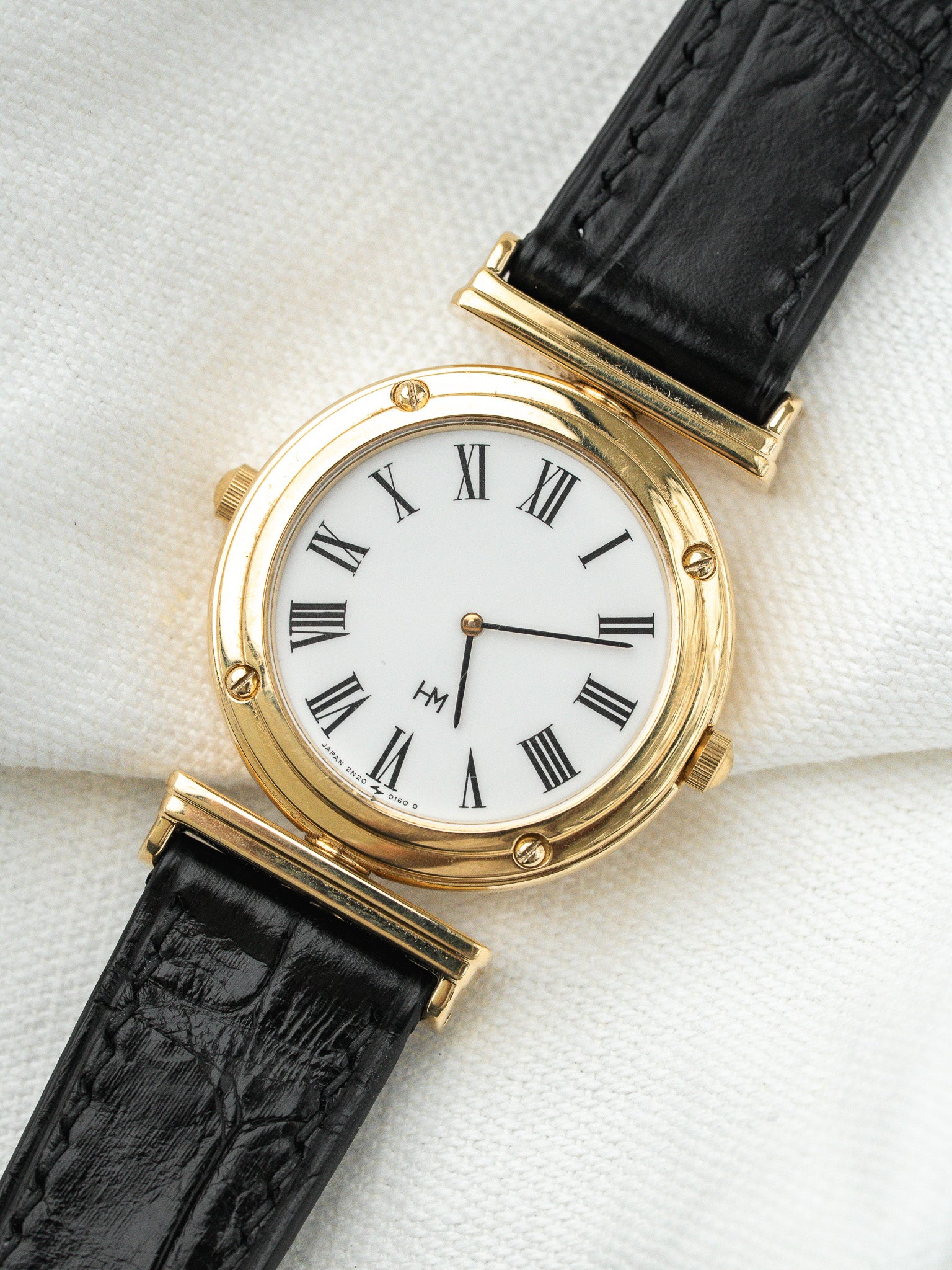 Montre HM vintage en or jaune, cadran blanc chiffres romains, bracelet cuir noir