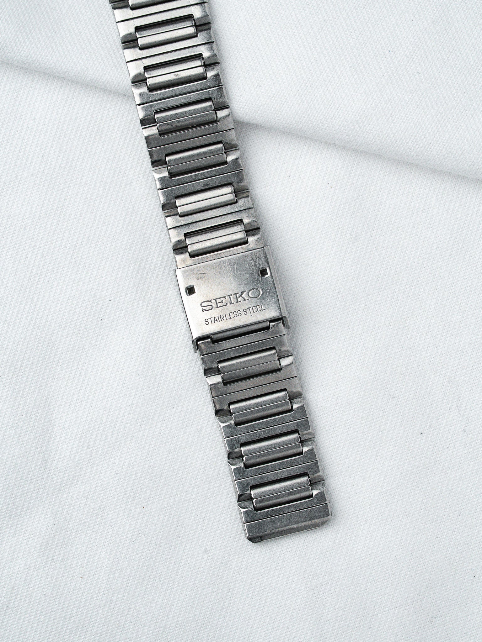 Seiko stainless steel watch bracelet with vintage link design on white fabric