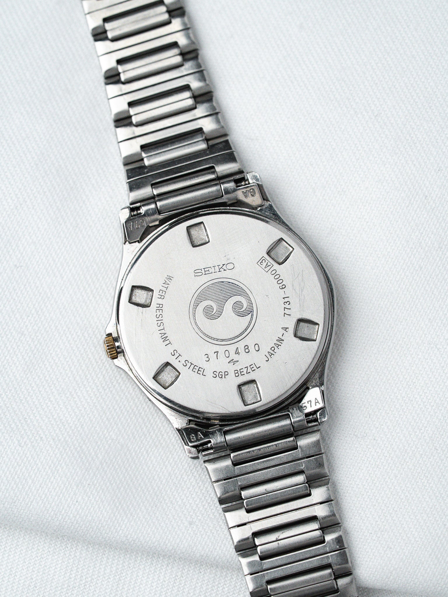 Seiko vintage watch back with stainless steel case and engraved details on white fabric