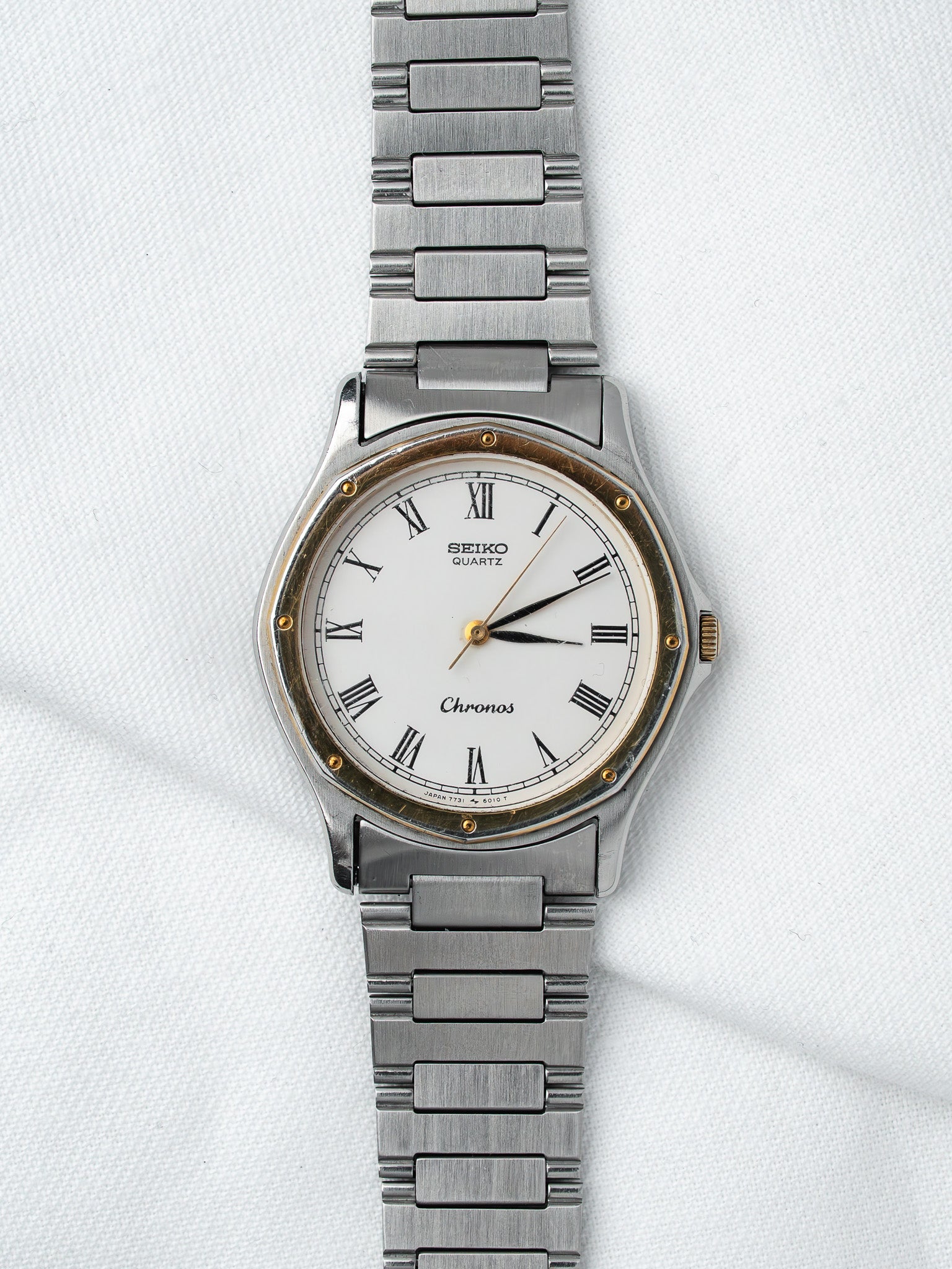 Seiko Chronos vintage quartz watch with white dial, Roman numerals, steel bracelet on white background