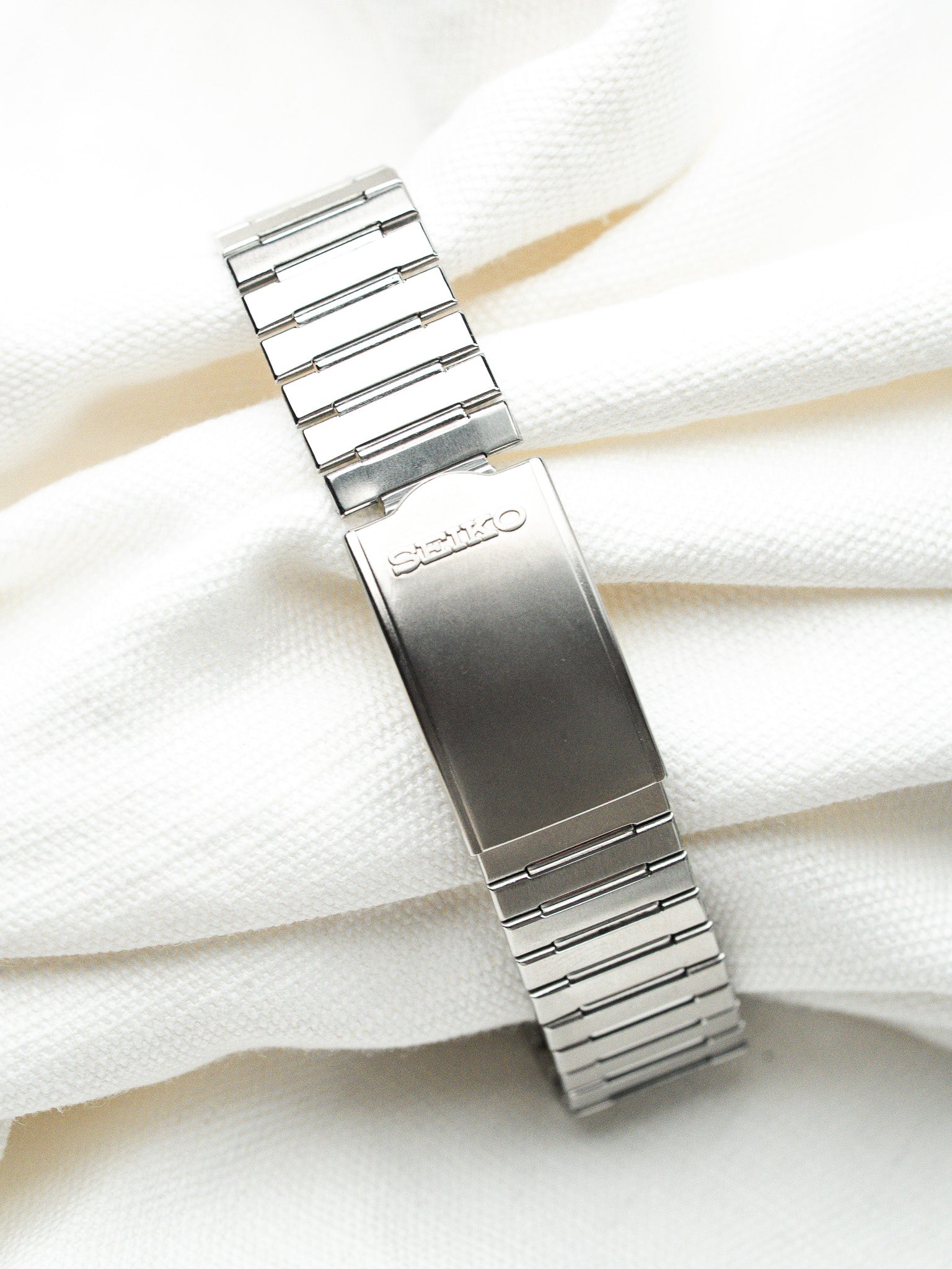 Seiko vintage watch bracelet in polished stainless steel, resting on white fabric