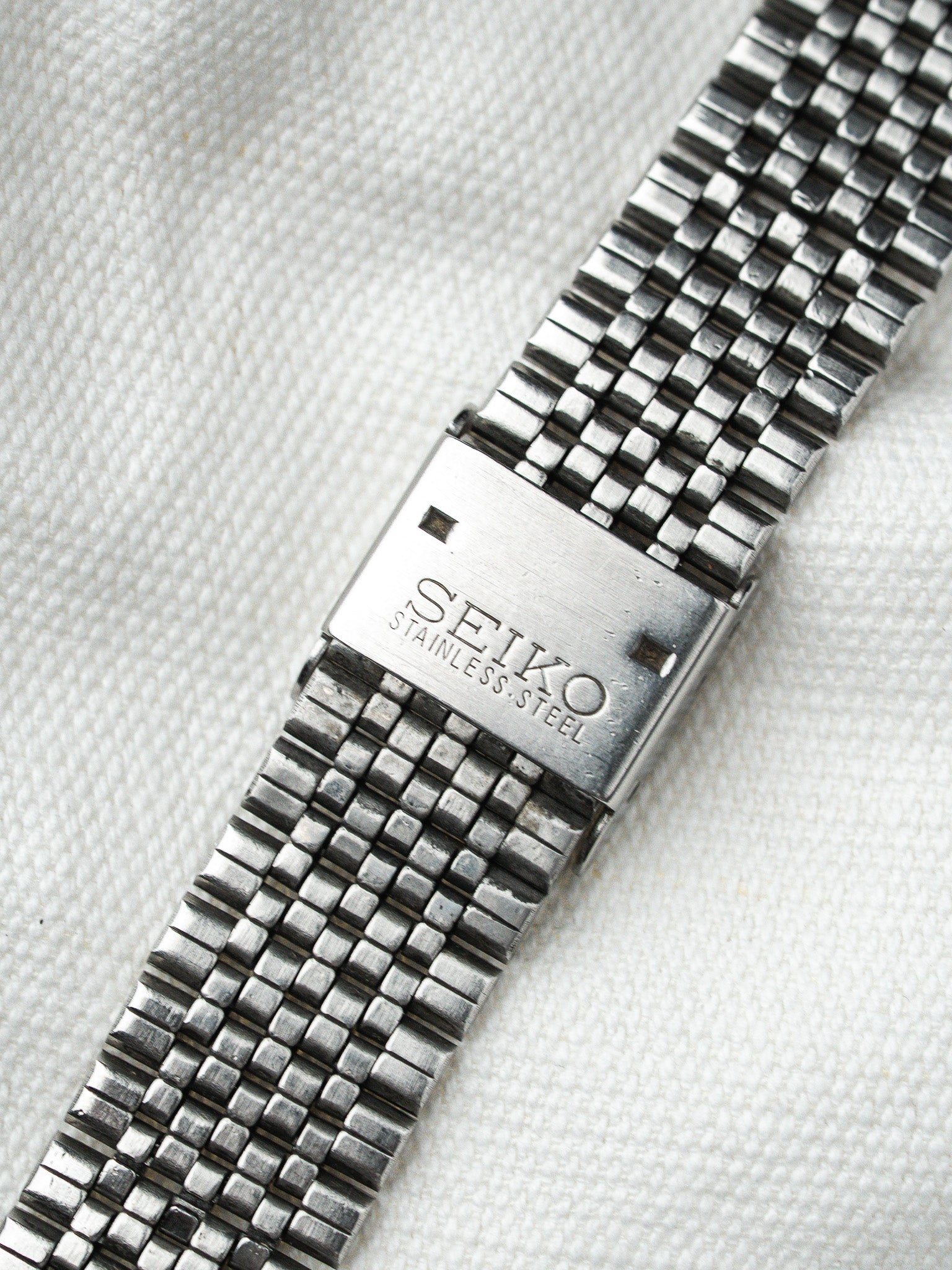 Seiko vintage stainless steel watch bracelet with textured mesh links on white fabric