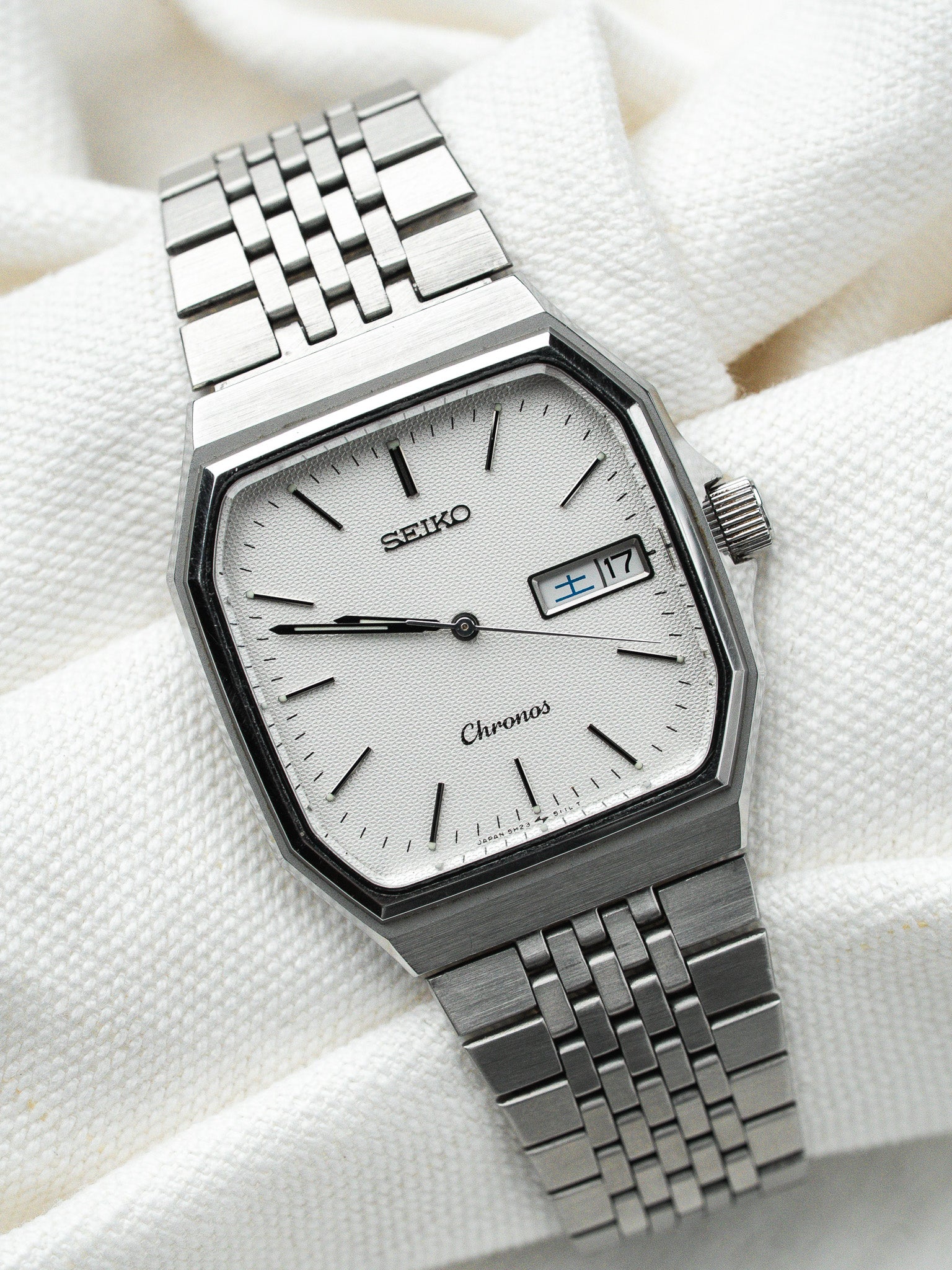 Seiko Chronos vintage watch with silver dial, octagonal case, and metal bracelet on white fabric