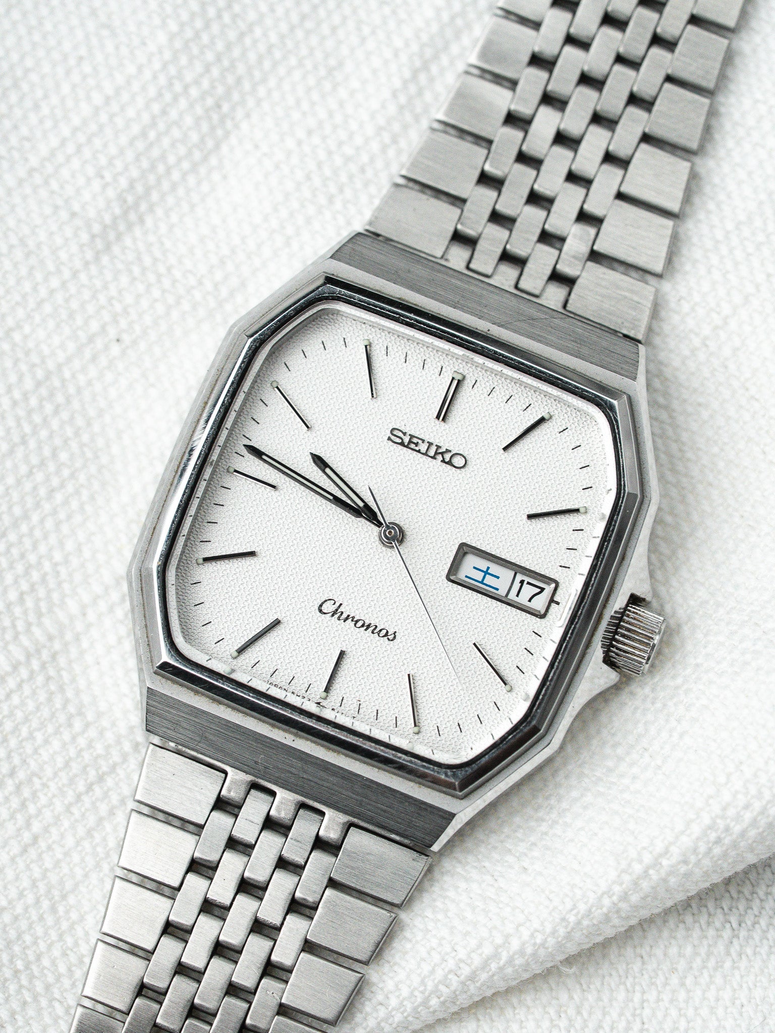 Seiko Chronos vintage watch with silver dial, octagonal case, and metal bracelet on white fabric