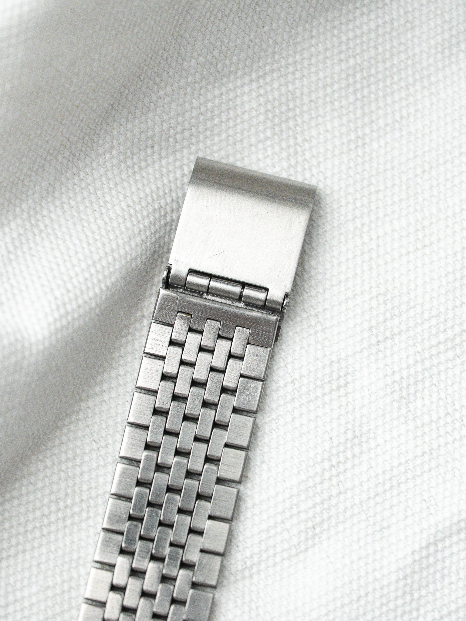 Vintage Omega steel bracelet with woven link design on textured white background