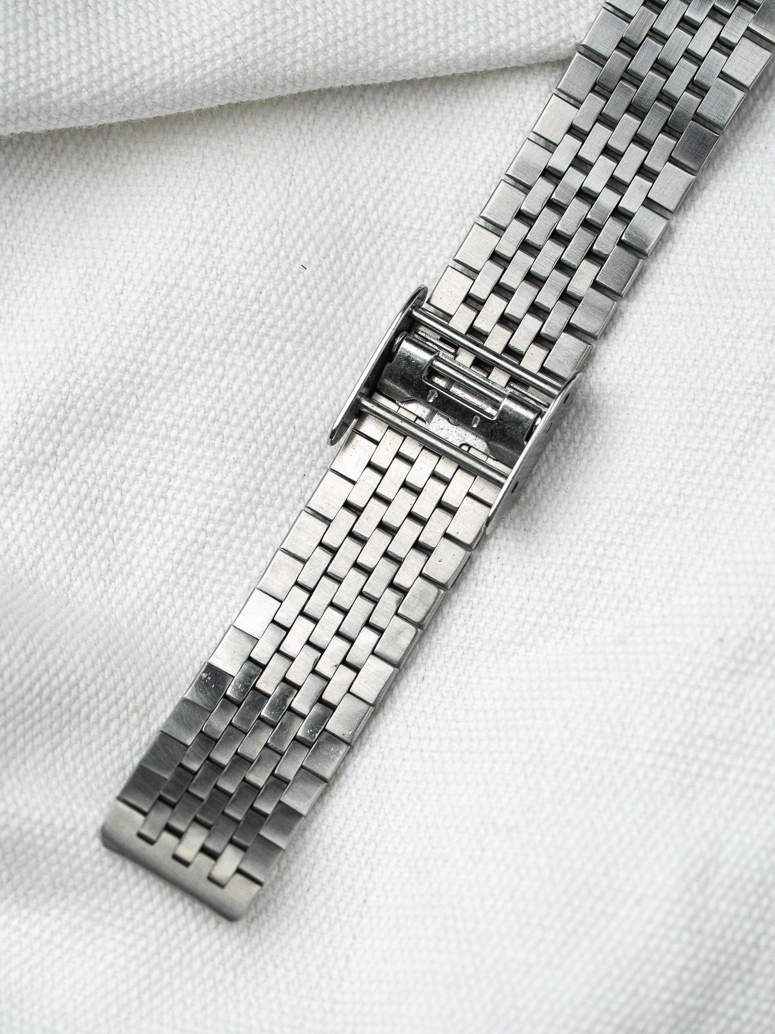 Vintage Omega Seamaster steel bracelet with brushed finish, displayed on white fabric
