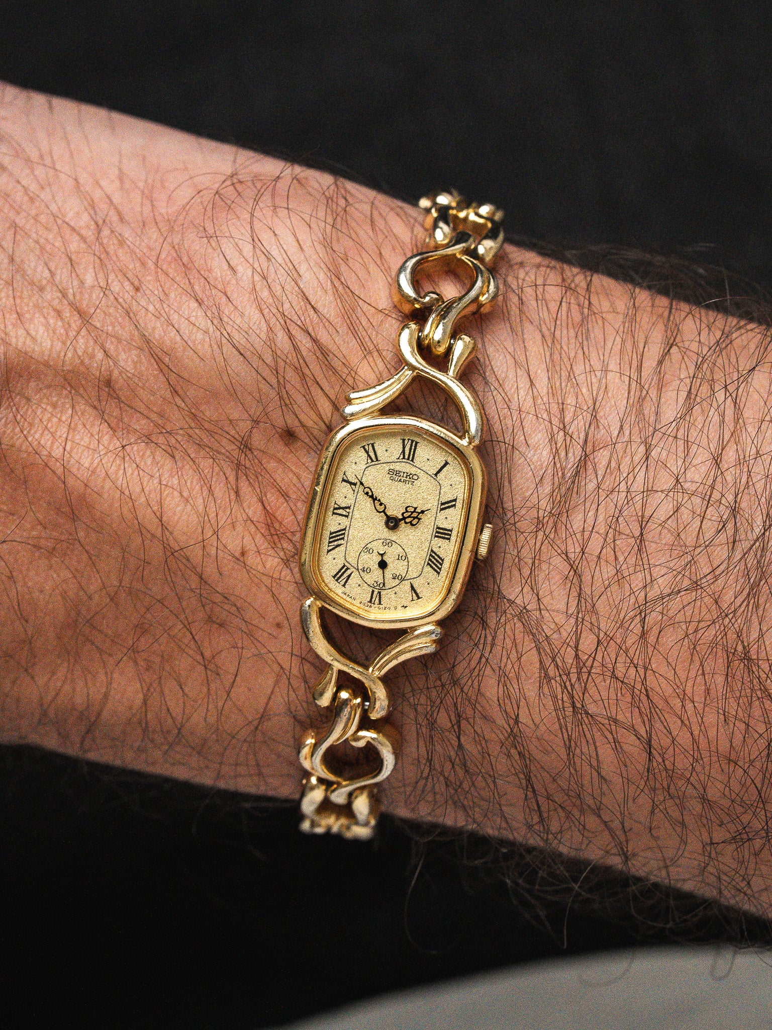 Seiko vintage watch with gold case, Roman numerals, and ornate bracelet worn on wrist