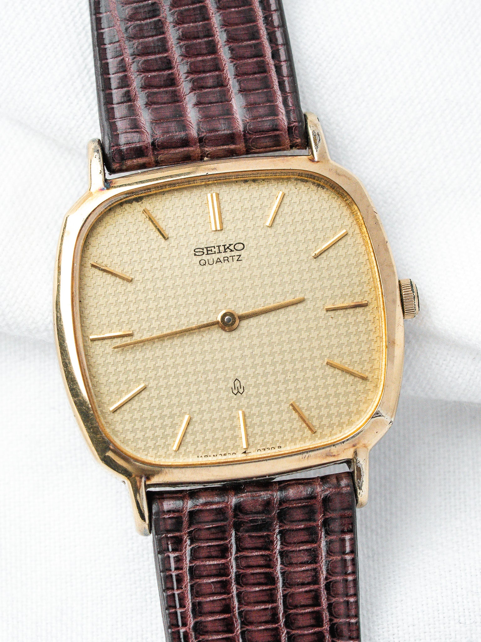Seiko Quartz vintage watch with gold case, textured dial, and brown alligator strap