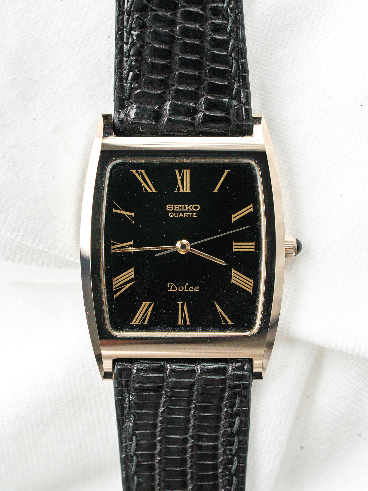 Montre Seiko Dolce vintage avec cadran noir rectangulaire et bracelet en cuir noir.