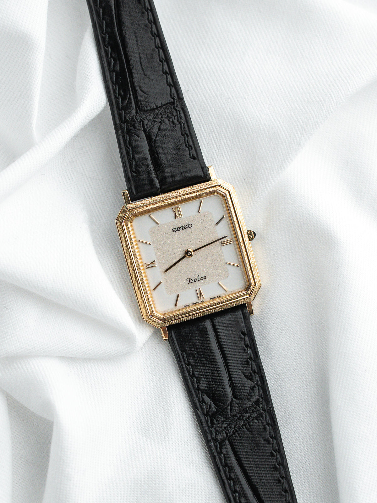 Montre Seiko Dolce vintage, boîtier rectangulaire doré, cadran blanc et bracelet cuir noir