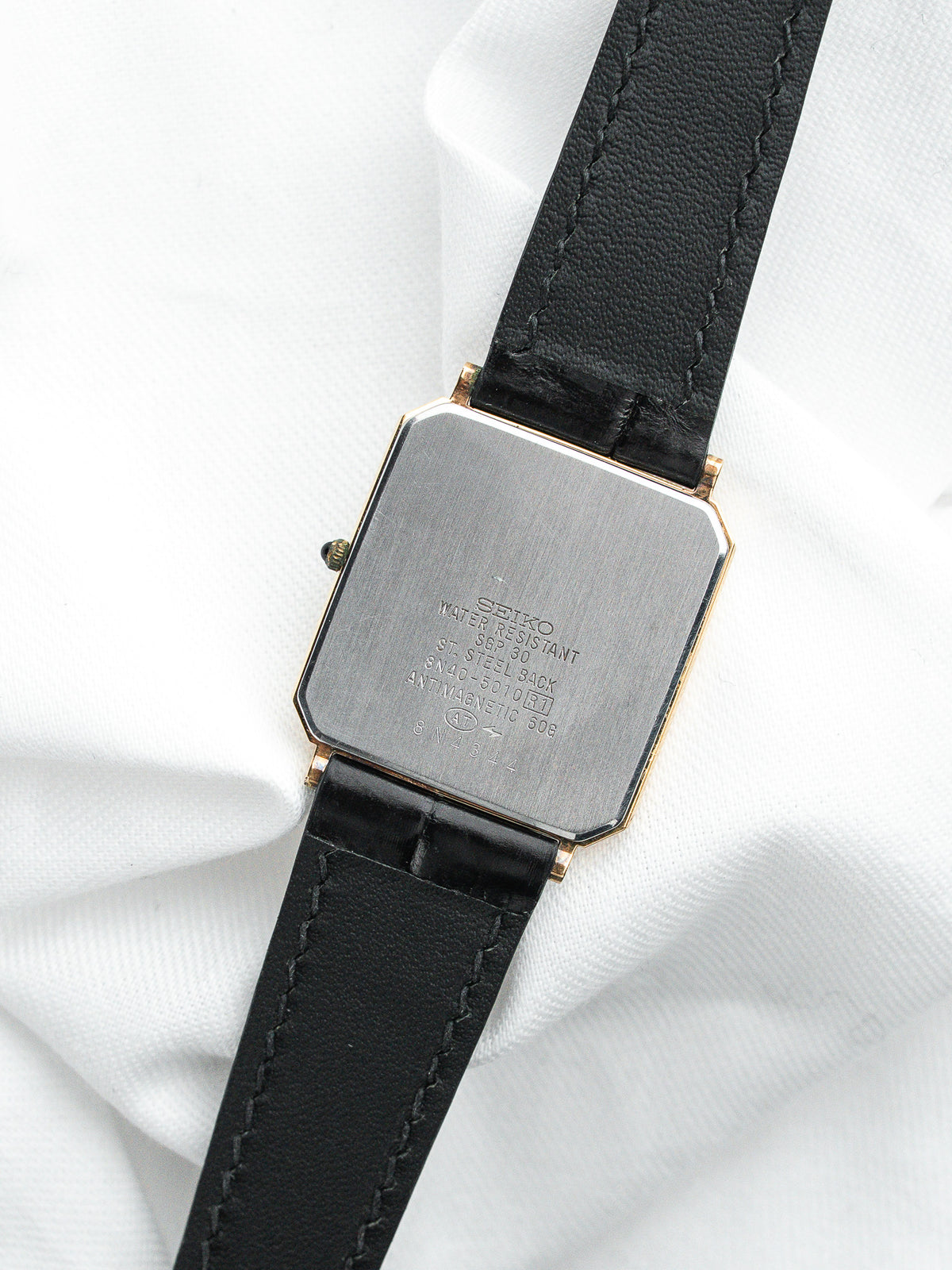 Dos d'une montre Seiko vintage en acier et or avec bracelet en cuir noir