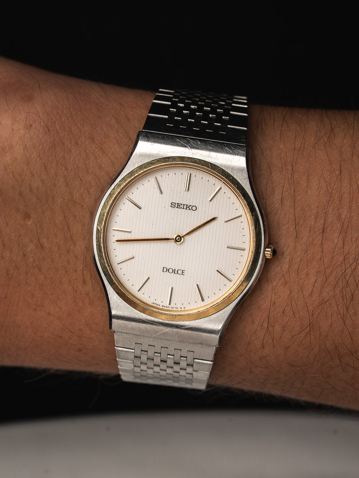 Montre Seiko Dolce vintage avec cadran blanc, lunette dorée et bracelet en acier argenté.