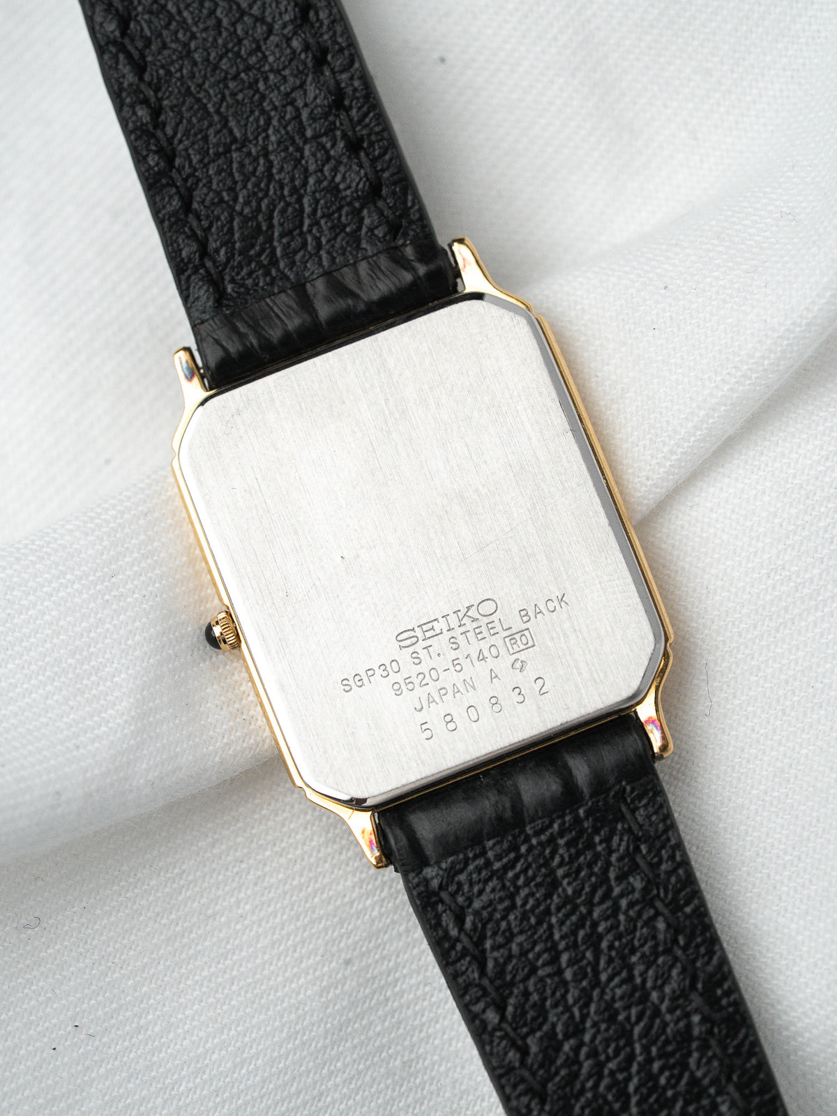 Seiko vintage watch with gold-tone case and black textured strap, steel back engraved