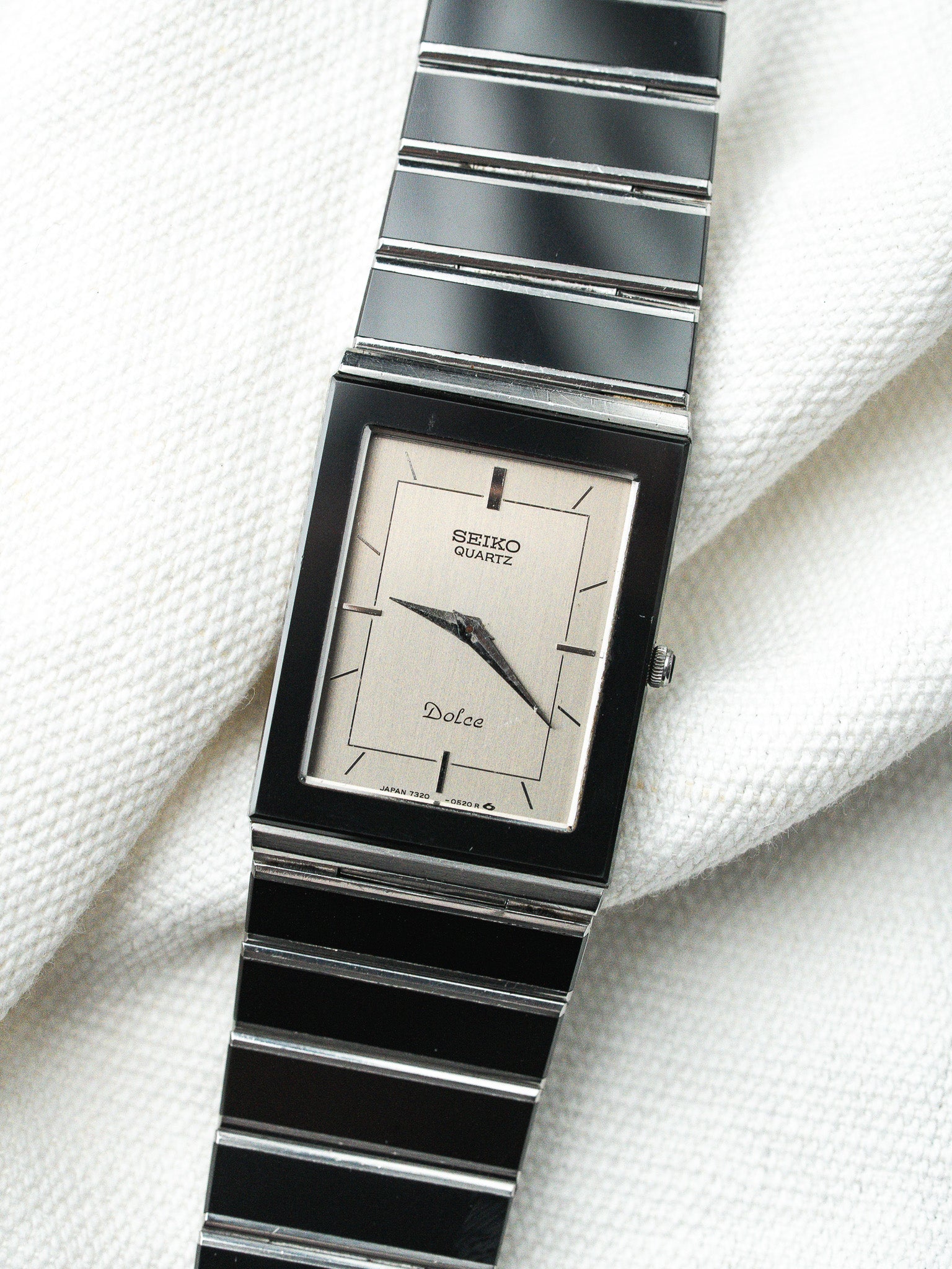 Seiko Dolce vintage quartz watch with silver dial and black bracelet on white fabric