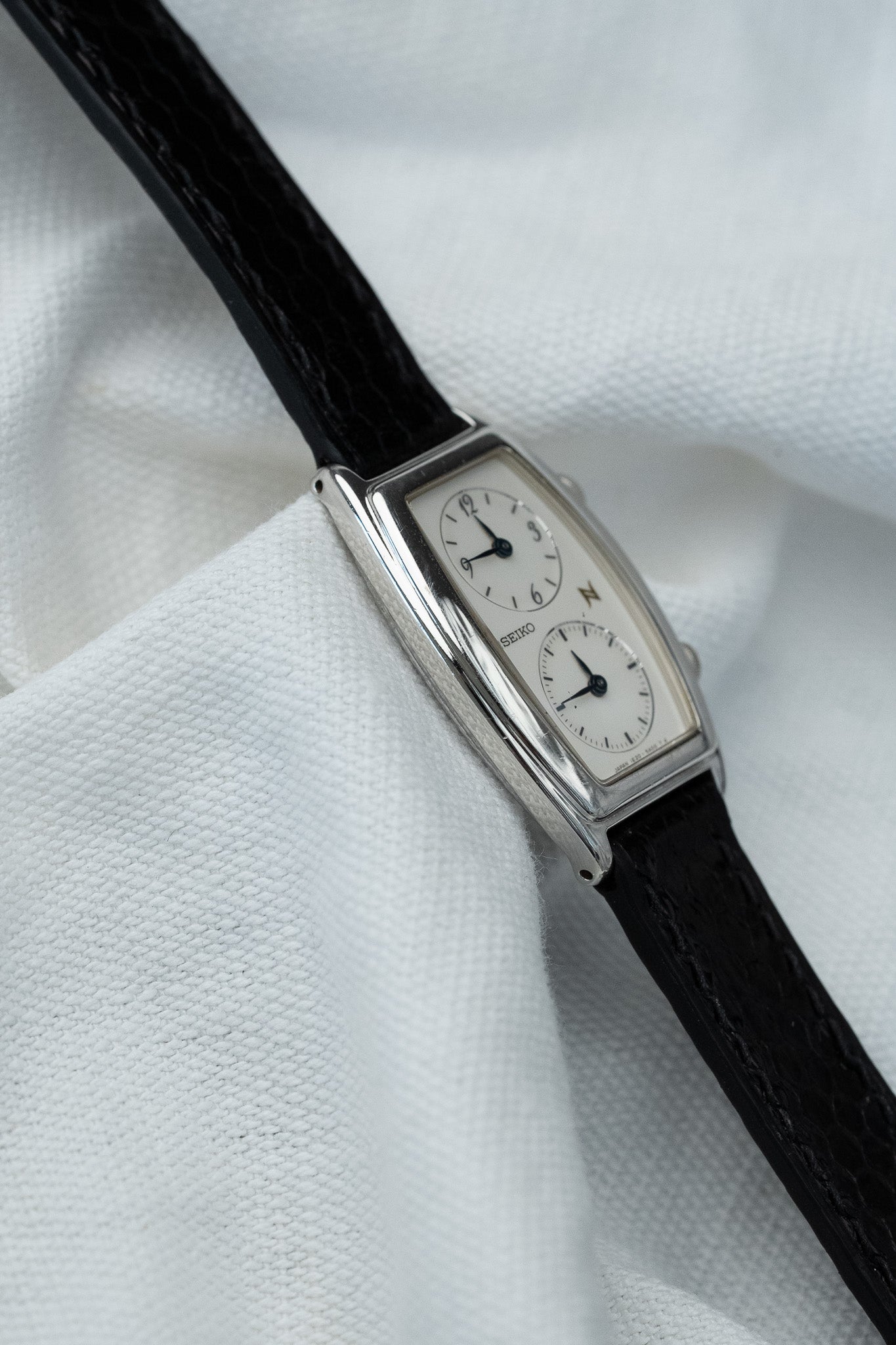 Seiko vintage rectangular watch with white dial, black leather strap on white fabric
