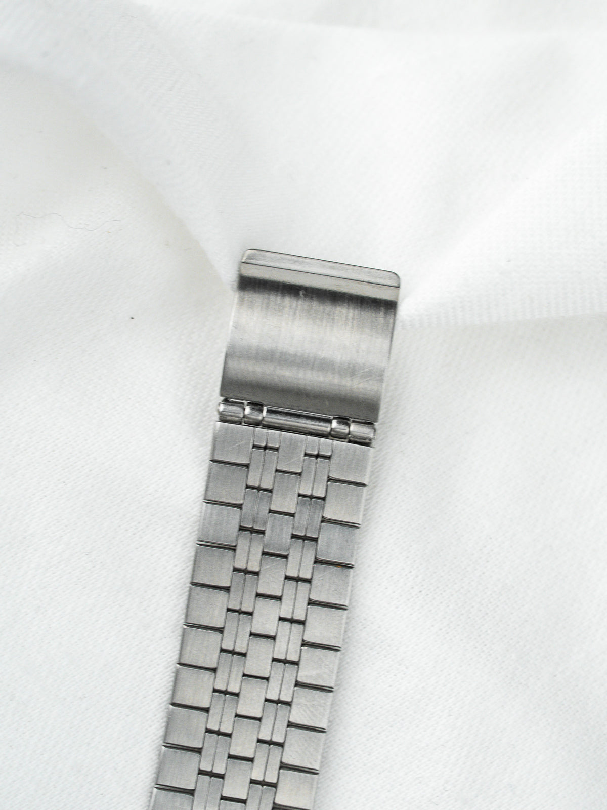 Bracelet de montre vintage en acier inoxydable avec maillons tressés sur fond blanc
