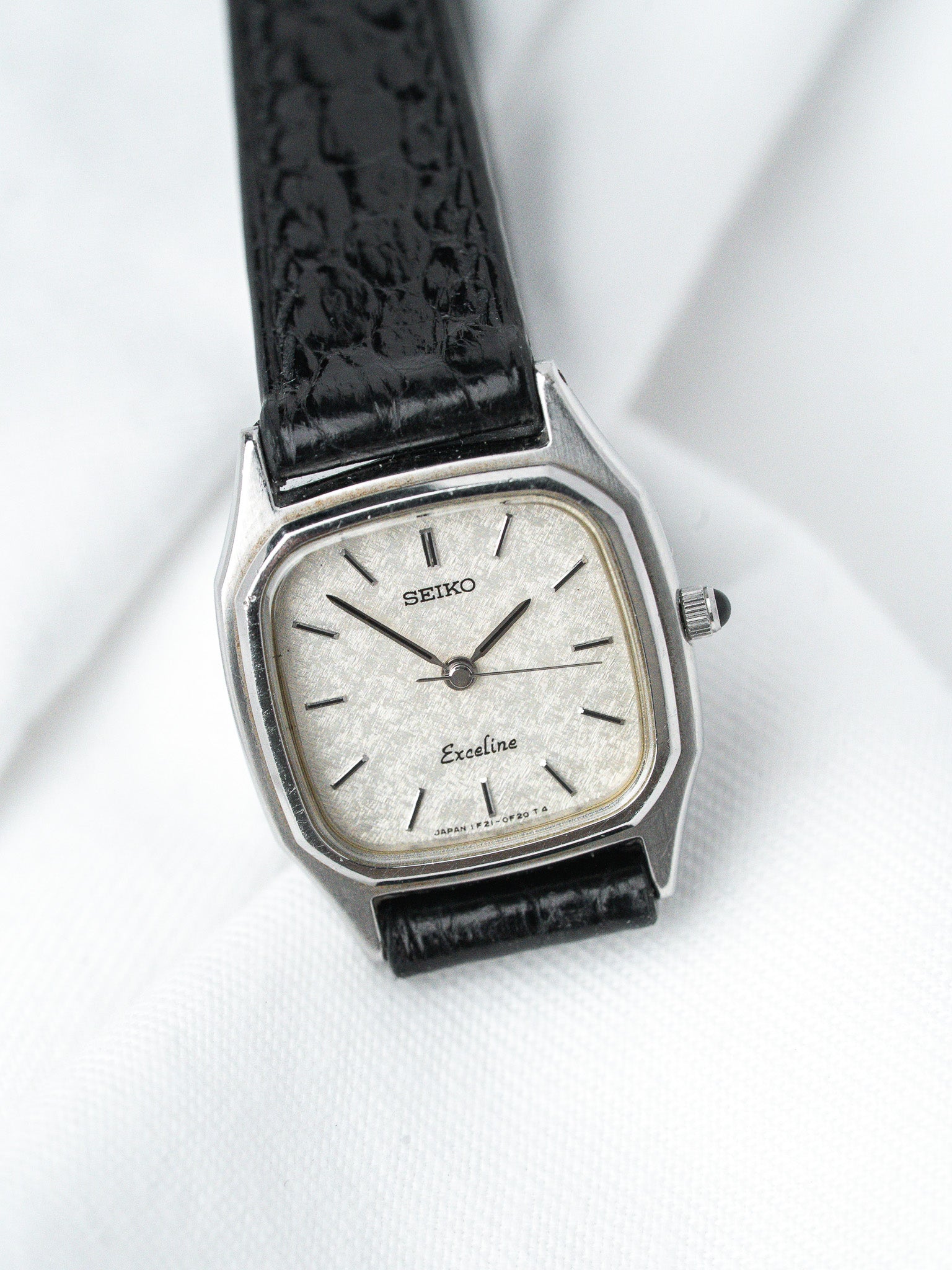 Seiko Exceline vintage watch with silver dial, black leather strap, octagonal case on white background