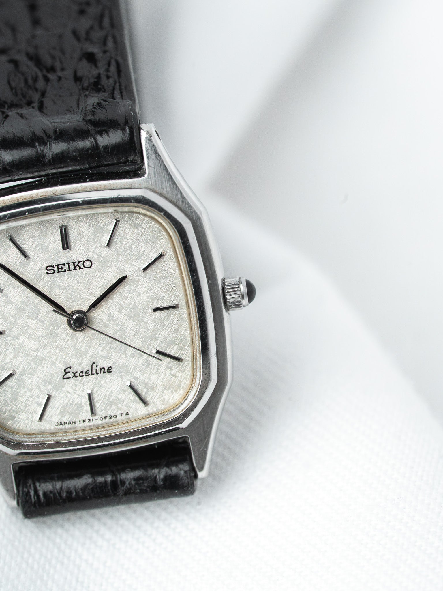 Seiko Exceline vintage watch with silver dial, black leather strap, octagonal case on white background
