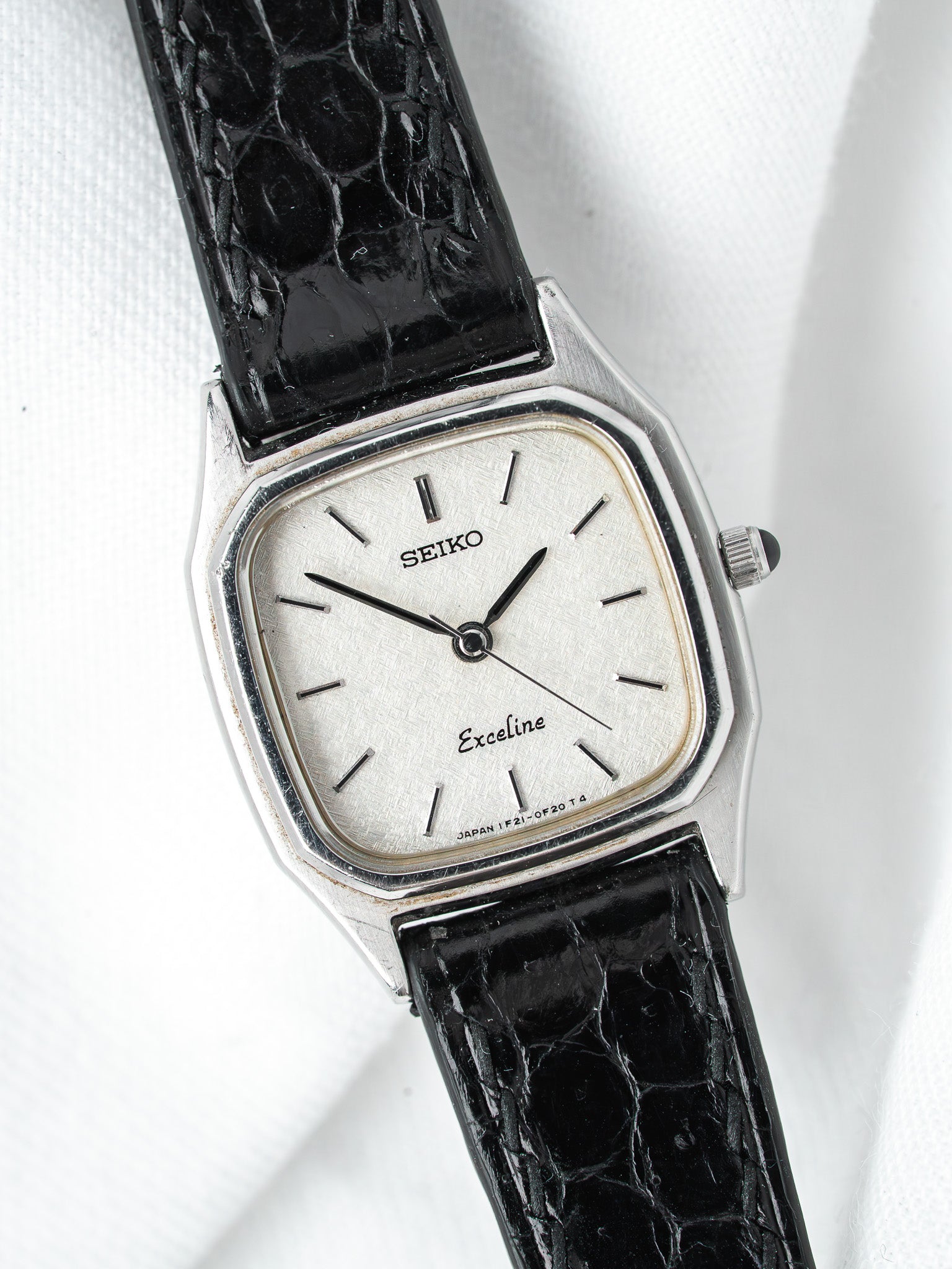 Seiko Exceline vintage watch with silver dial and black crocodile strap on white background